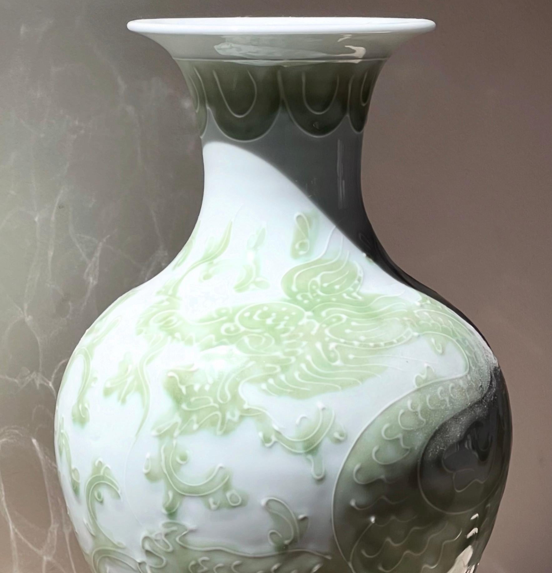 Rarissimo vaso in porcellana smaltata con motivo di drago cinese di Tozai Home, XX secolo. Questo pezzo brilla in bianco avorio con un motivo decorativo in rilievo in verde acqua, raffigurante un drago che avvolge l'intero vaso. Con una forma