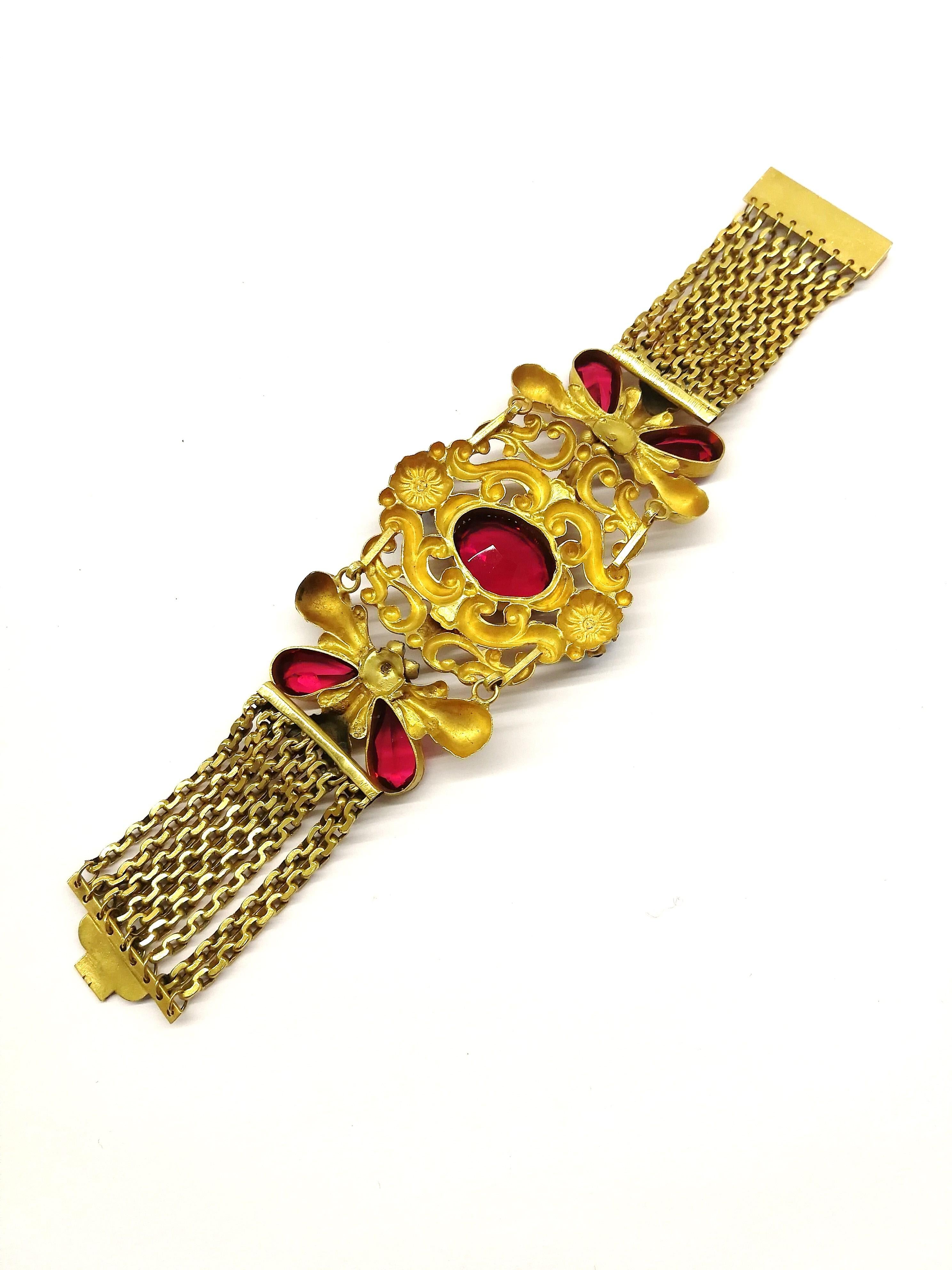 A very striking and dramatic bracelet in a Victorian or Baroque style, with ruby, pearl  and turquoise pastes of varying sizes. Set with an articulated metal centrepiece, nine rows of flat chain form part of the bracelet, meeting in a firm and fixed