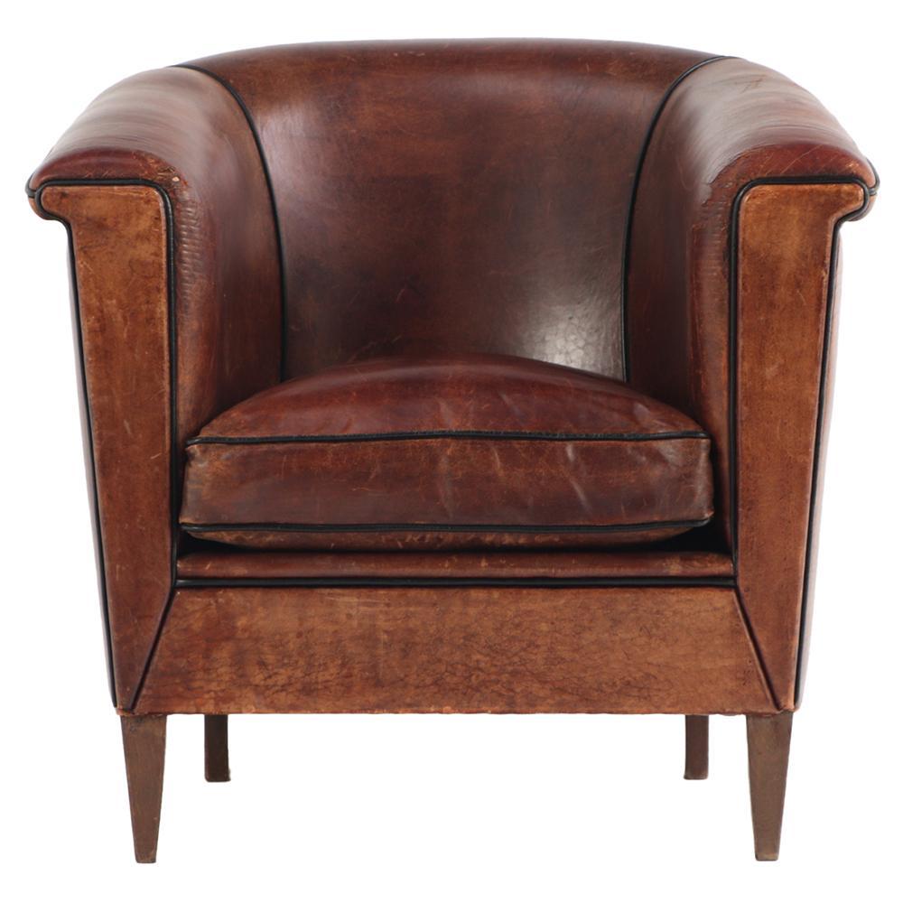 Upholstered in rich, patinated leather that beautifully reflects its age and use, this chair features a classic, generously proportioned silhouette with a deep seat and gently rounded back for comfort and support. Set on square, tapering wooden