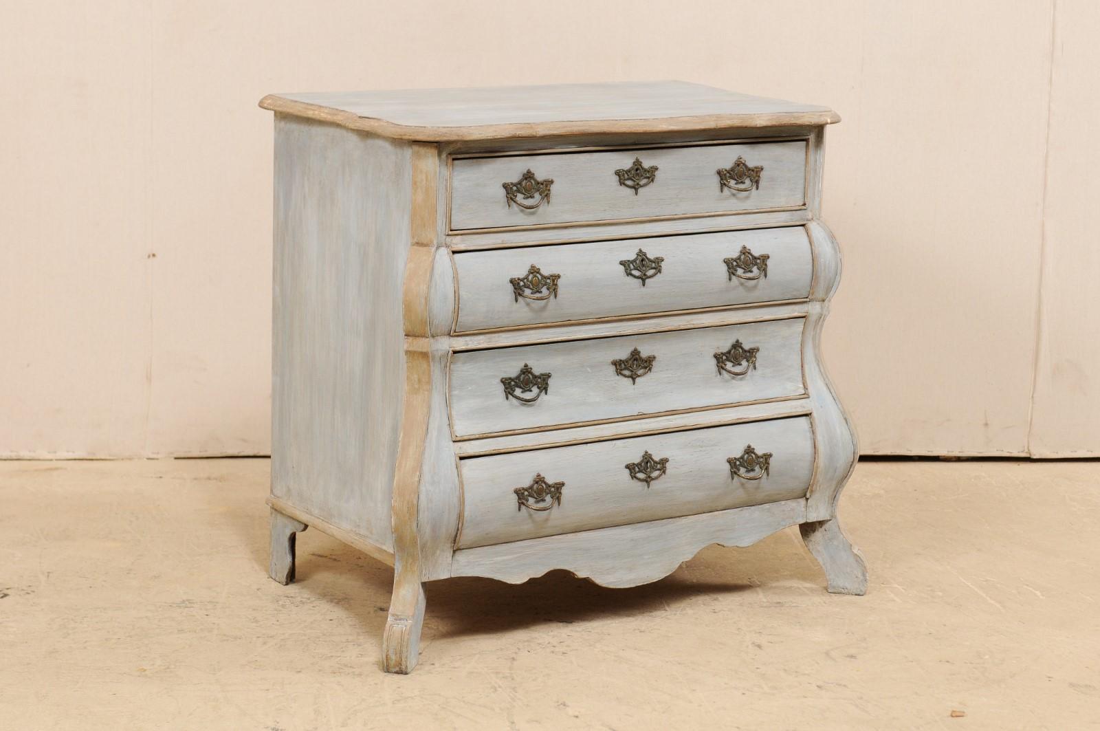 A Dutch bombé front painted wood chest of drawers from the early 20th century. This antique chest from the Netherlands features a Classic Dutch style with the shapely top resting above the serpentine front with exaggerated side posts, and fitted
