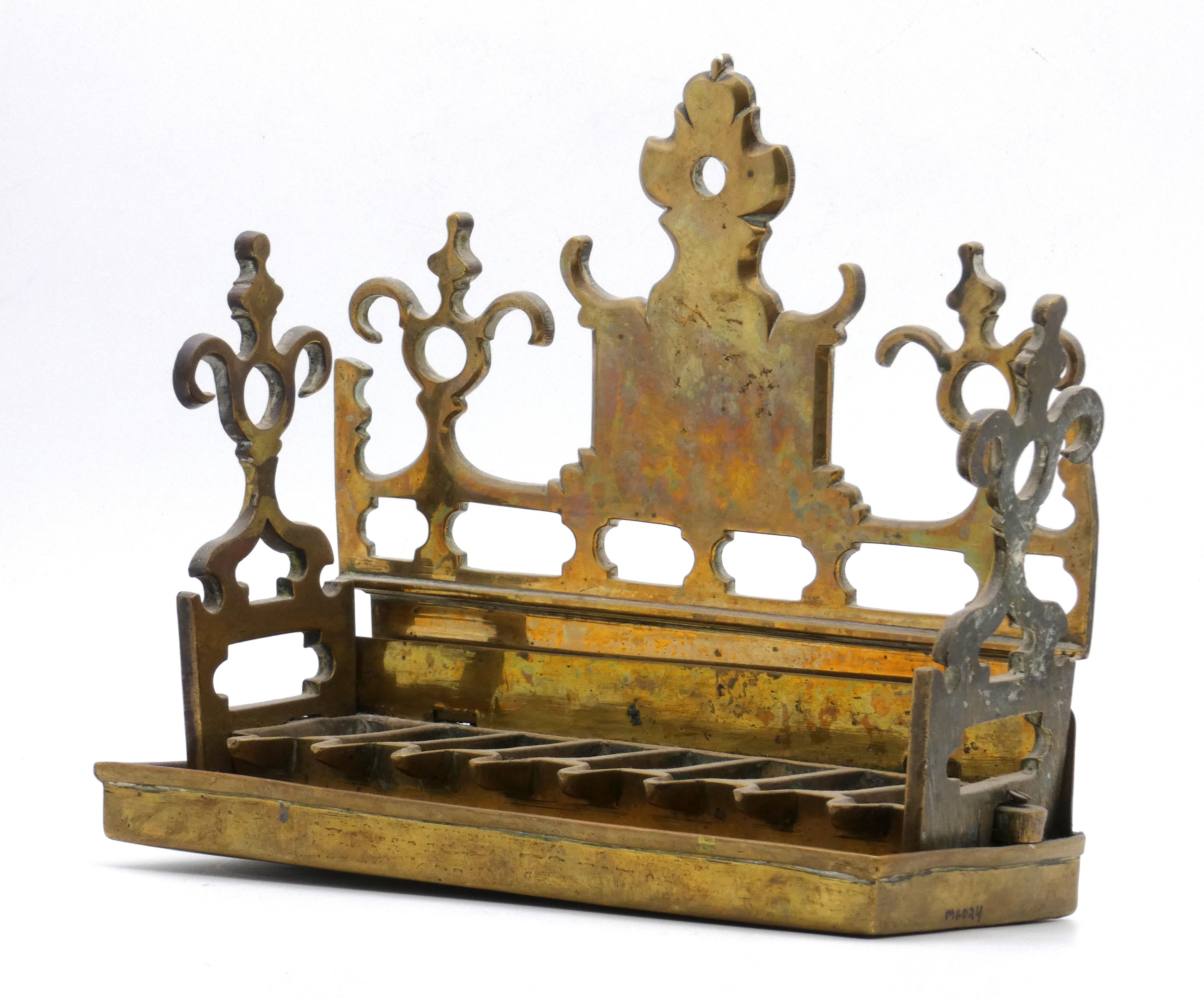 Dutch brass Hanukkah lamps like this one were made in the 17th century for the common Jewish household as most were accustomed to owning brass Hanukkah lamps.

Hanukkah lamp features an openwork backplate and side panels both surmounted with