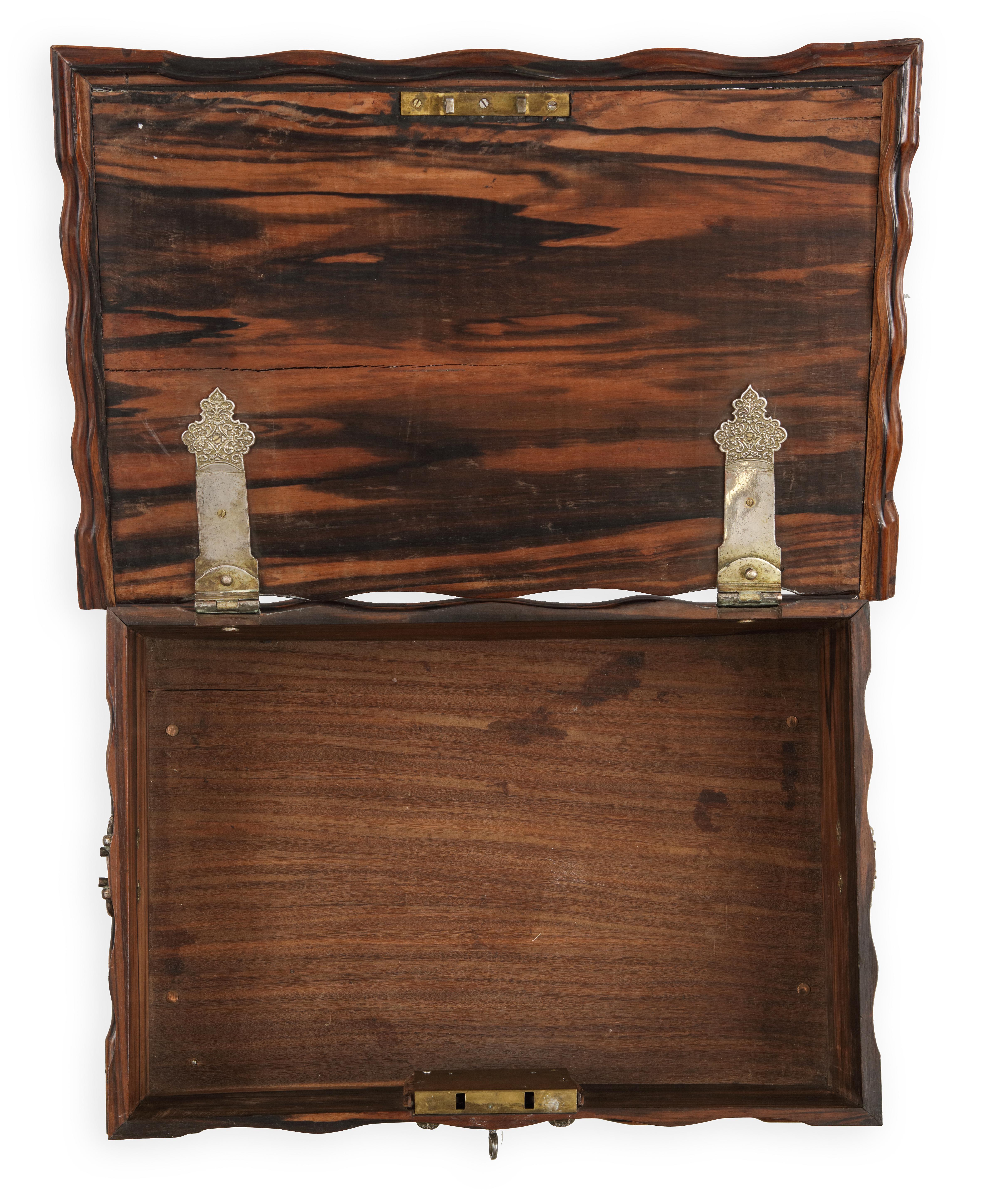 A Dutch-colonial Sri Lankan coromandel wood document box with silver mounts
Probably Galle, 18th century

H. 19 x W. 49 x D. 33 cm


The chest with waving sides and front has applied silver escutcheons and loop handles on the sides, with two