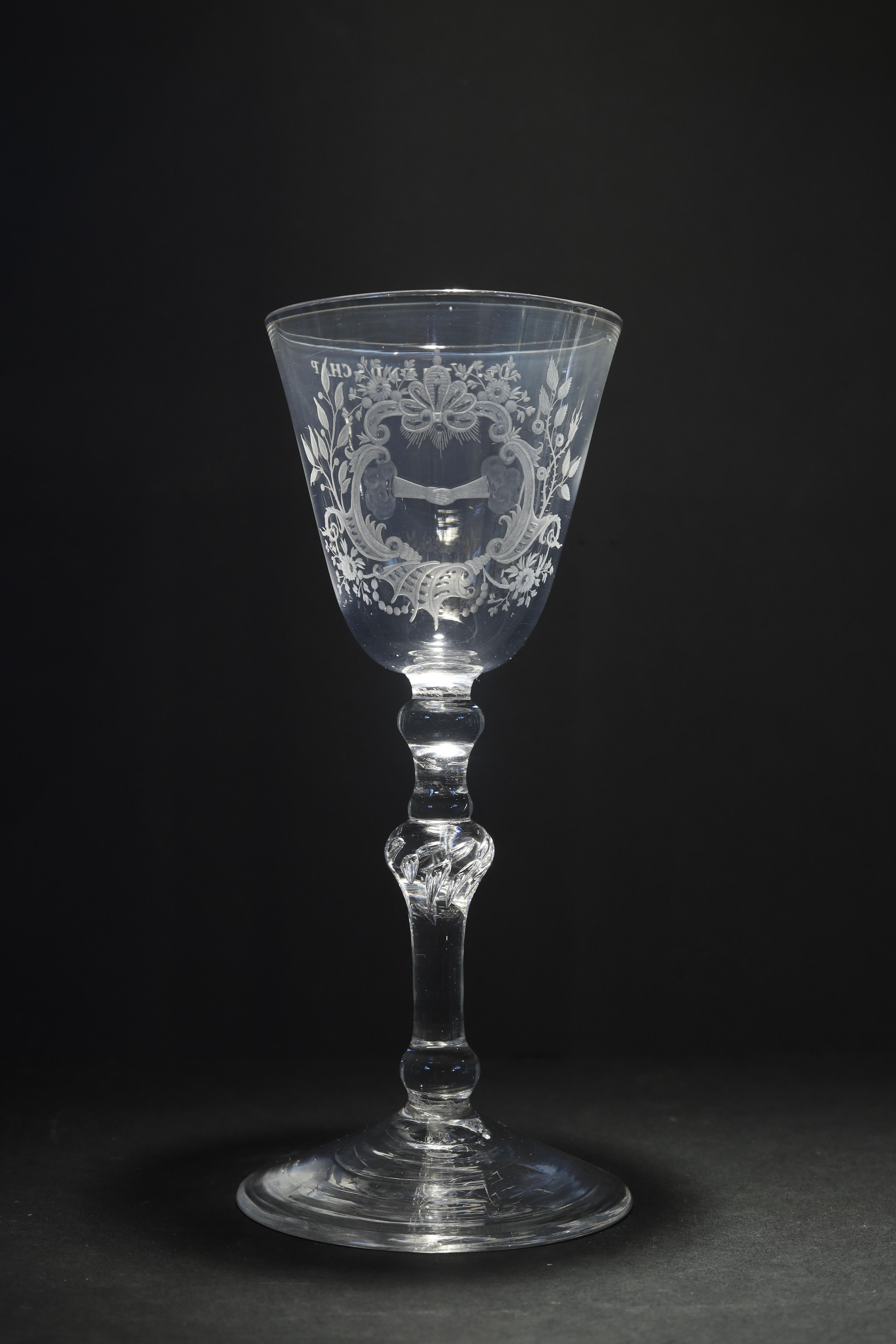 The Netherlands or England
Engraving: The Netherlands
Circa 1750

An elegant Newcastle? Dutch engraved baluster glass with a fine engraving of two shaking hands in a Rococo-style cartouche symbolizing friendship. 
On the back: De Vriendschap: The