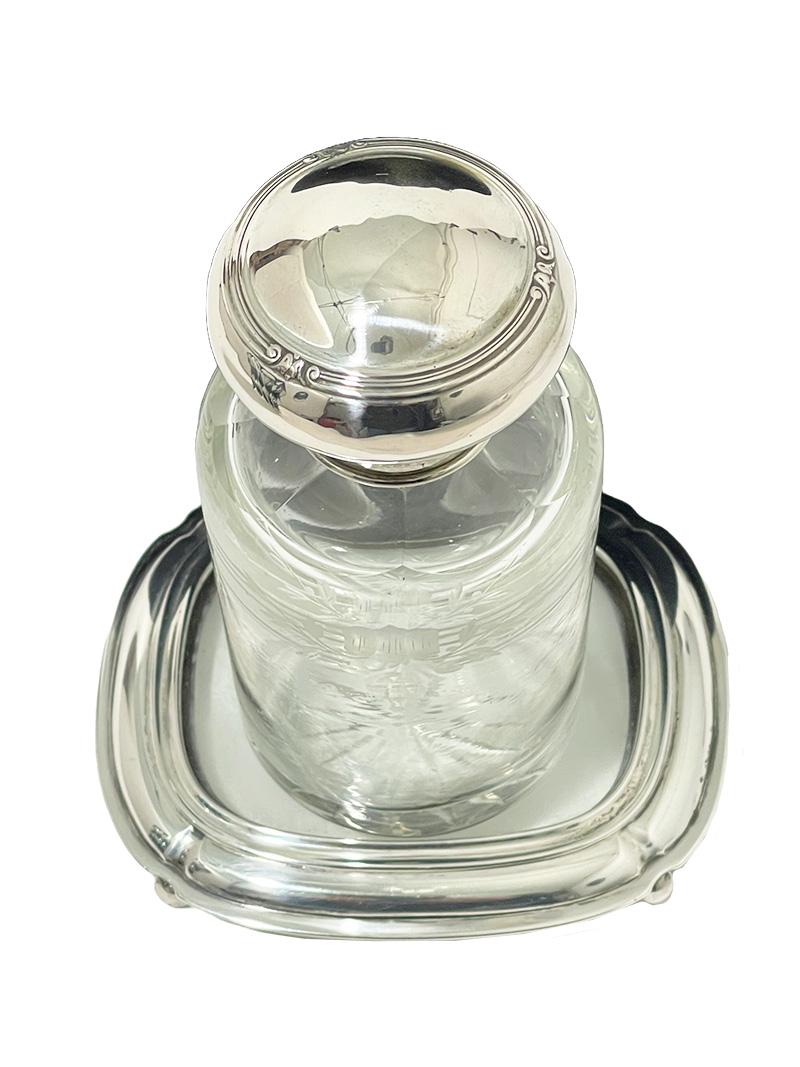 Ein holländisches Parfümfläschchen auf einem Untersetzer mit Silber, 1918

Eine holländische Kristall mit Silber Parfüm Flasche auf einem Glas mit Silber Untersetzer. Die Achterbahn steht auf vier Kugelfüßen. Der Parfümflakon ist aus Kristall mit