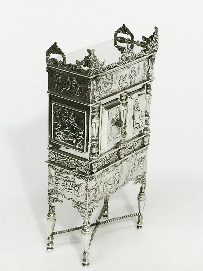 Dutch Silver Doll House Miniature Cross-Leg Cabinet, Herbert Hooijkaas, 1901

A Dutch silver Doll House 20 cm high miniature cross-leg cabinet on bottle legs with twisted connection in Rococo style with columns and 2 doors with an interior with
