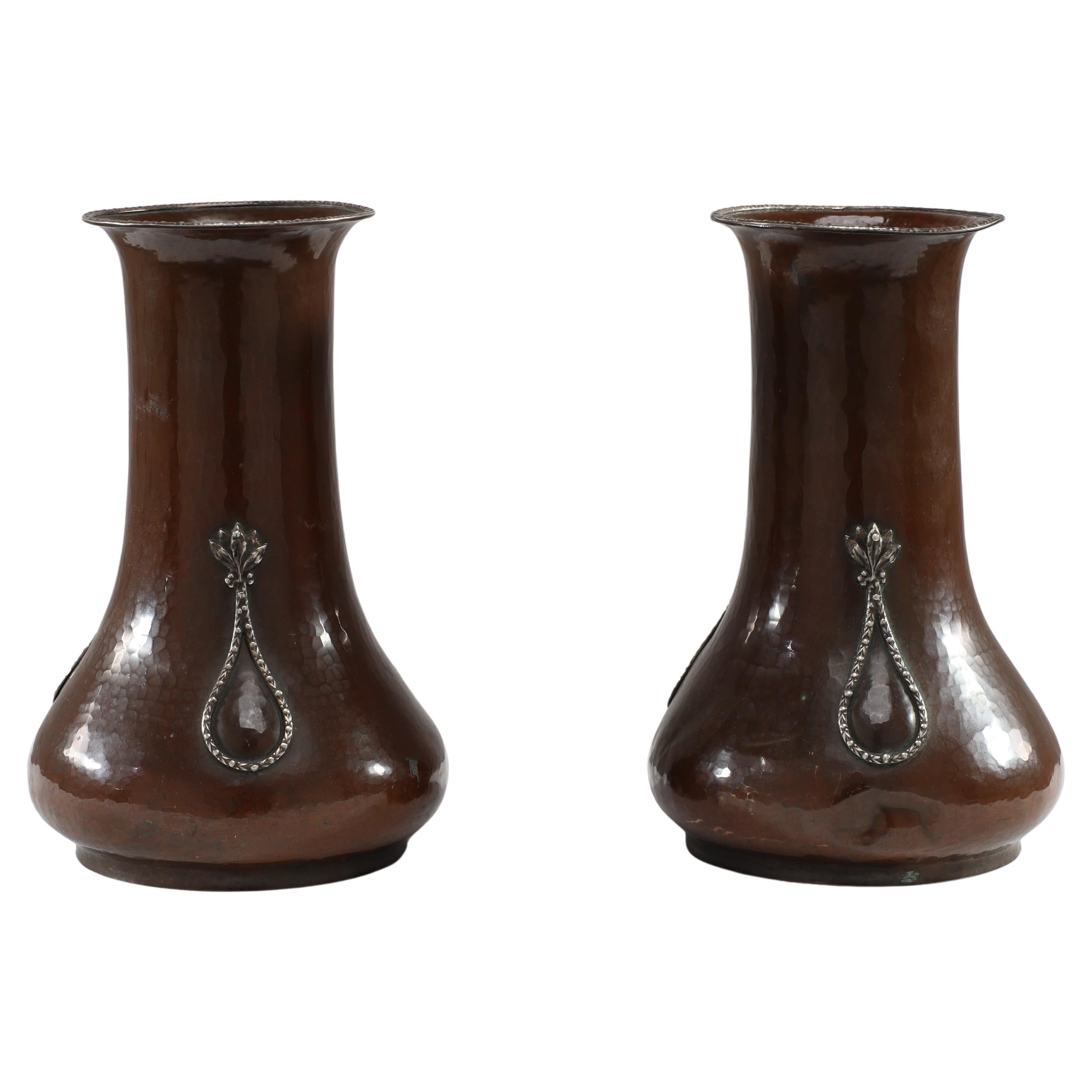 A E Jones. A pair of hand-hammered copper vases with silver teardrop decoration
