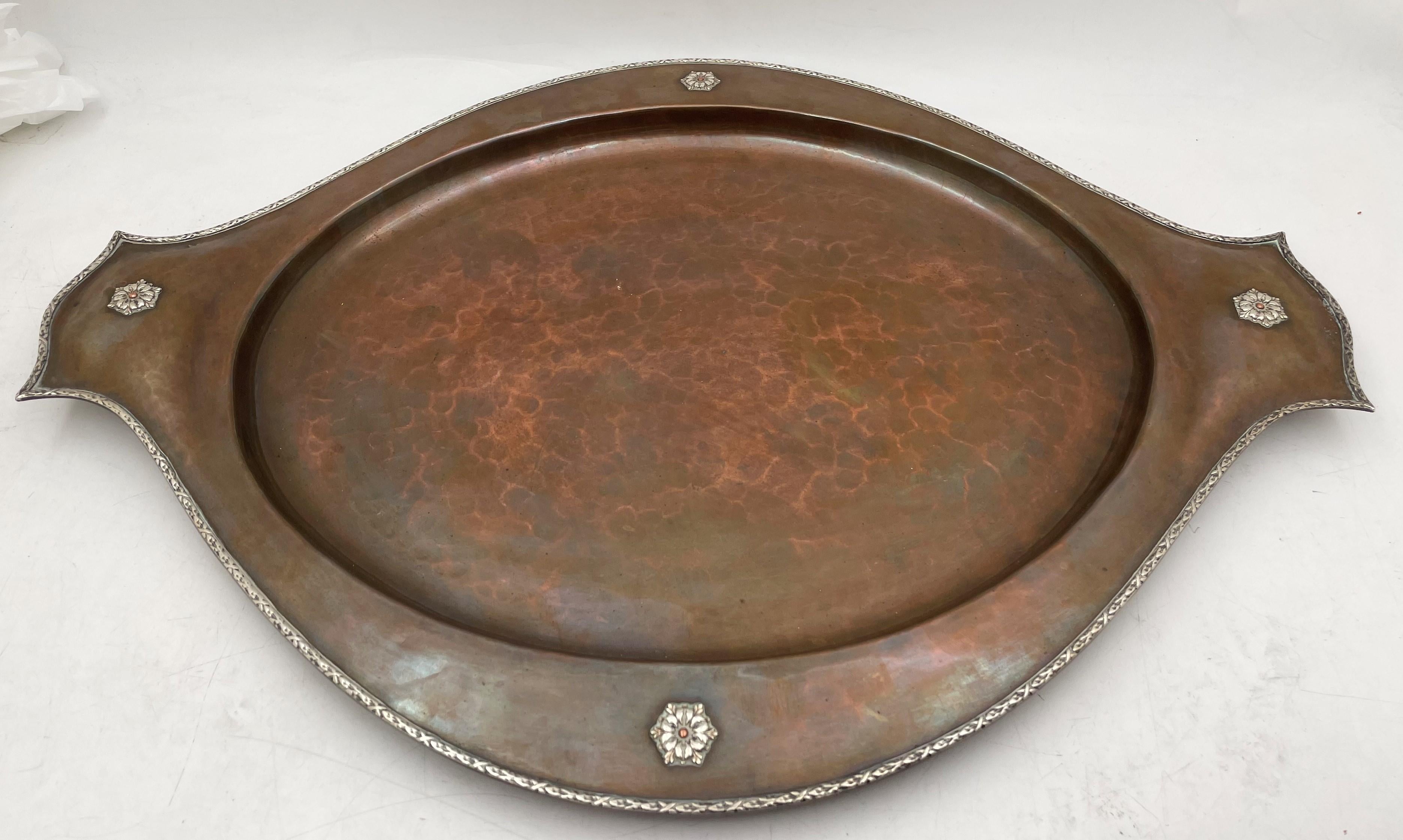 A. E. Jones copper pair of vases and tray in Arts & Crafts style, adorned with applied sterling silver motifs, from the early 20th century. The vases measure 7 3/4'' in height by 3 1/2'' in diameter at the top. The tray measures 20 1/2'' in length