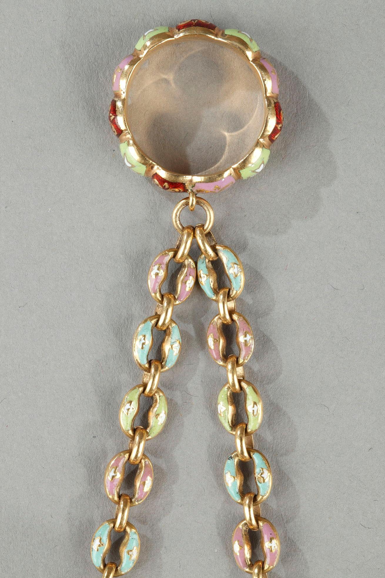 Vinaigrette in Form eines Korbes, der an einer goldenen Gliederkette an einem kleinen goldenen Ring aufgehängt ist. Die Seiten, der Boden und der gewölbte Deckel sind mit mehrfarbigen Blumenbouquets auf einem durchscheinend rot emaillierten, mit