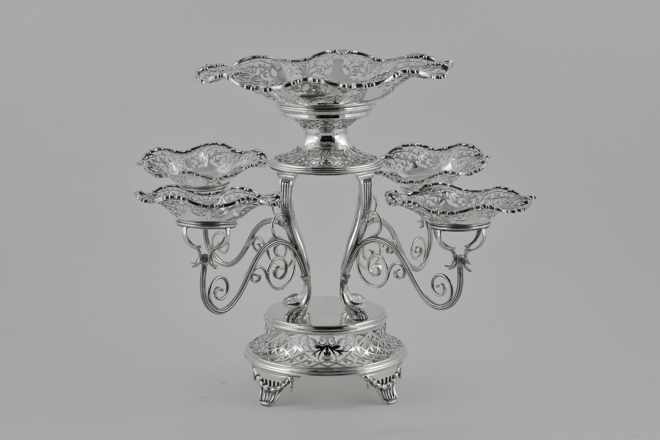 A 5 dish epergne by The Alexander Clark Company London. Formed with 5 removable pierced dishes, the circular foot raised on four feet, the frame and branches decorated throughout with elaborate pierced work and with scrolling branches.


The