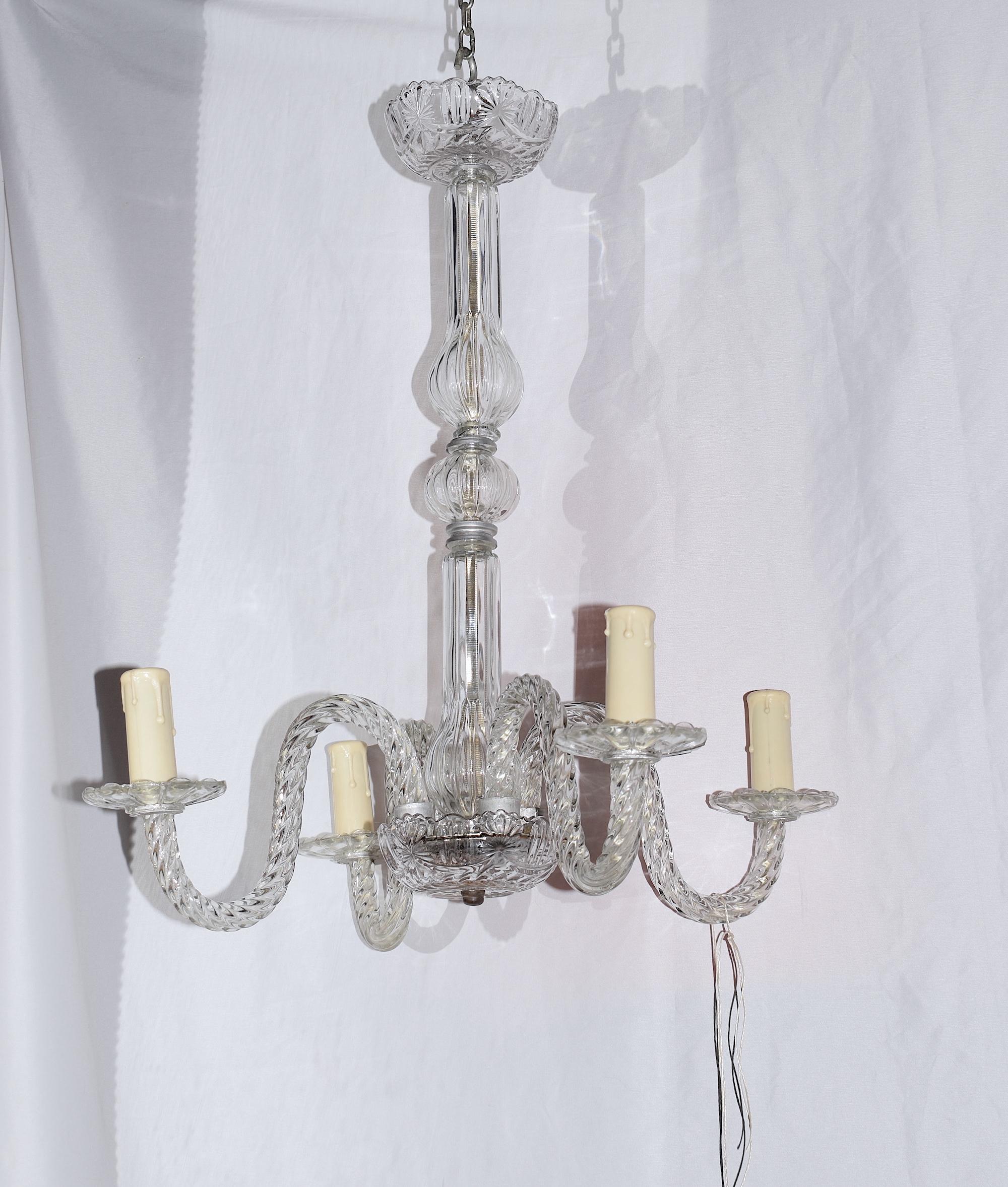 A small but grand early 20th century glass chandelier. This chandelier is elegant and radiated the style of Murano Ressonico chandeliers that are made in Venice. It has four twisted glass arms that connect to electric light bulbs. All original parts