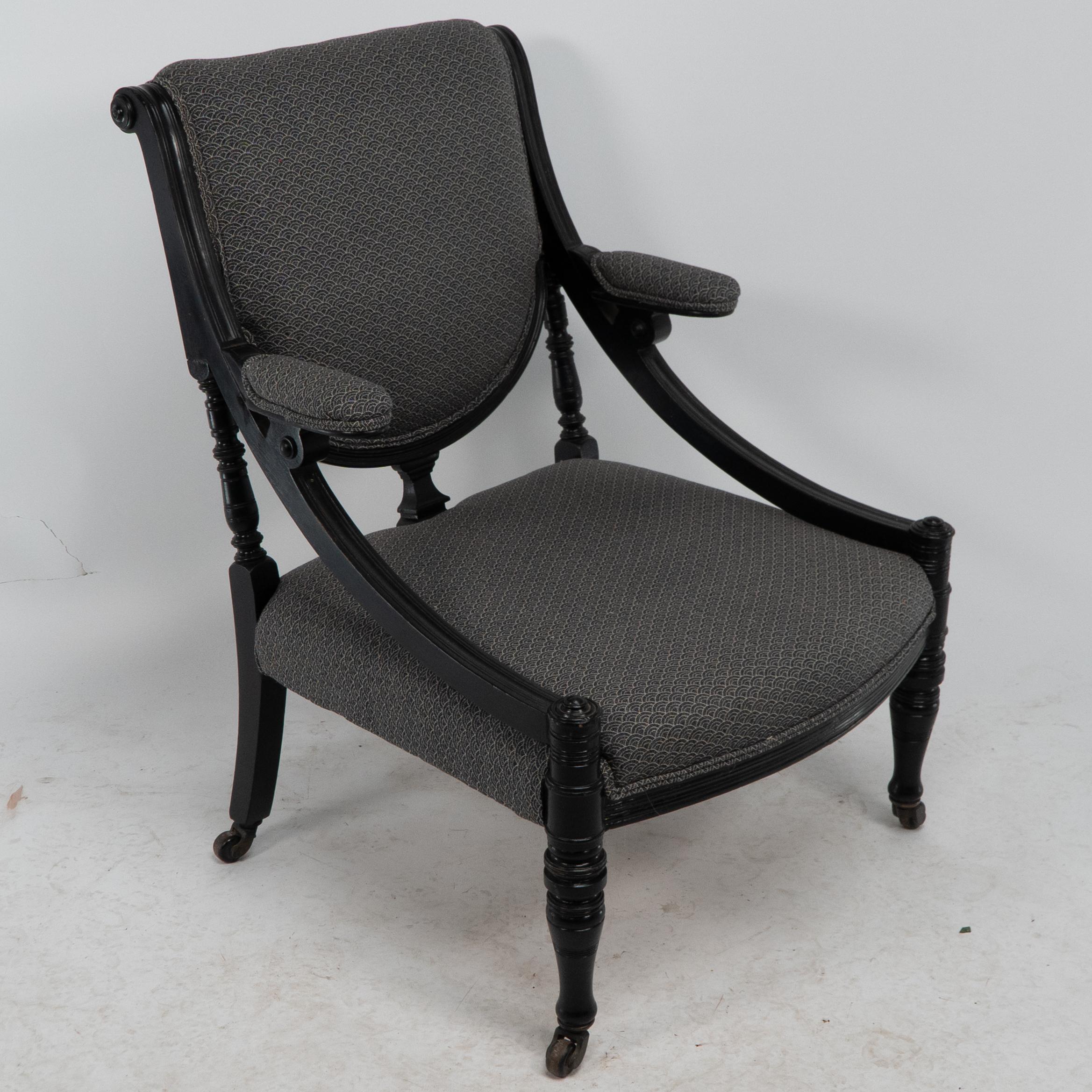 Ein stilvoller ebonisierter Sessel des Aesthetic Movement mit geschwungener Seitenschiene, in die die gepolsterten Armlehnen eingearbeitet sind, die zurückgesetzt sind, um die wunderbaren Reifenkleider der viktorianischen Zeit aufzunehmen, so dass