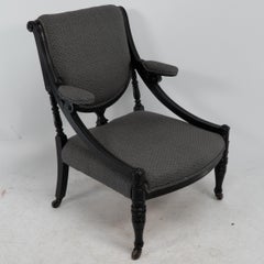 Una poltrona dell'Aesthetic Movement ebanizzata e imbottita, con binari laterali a sbalzo.