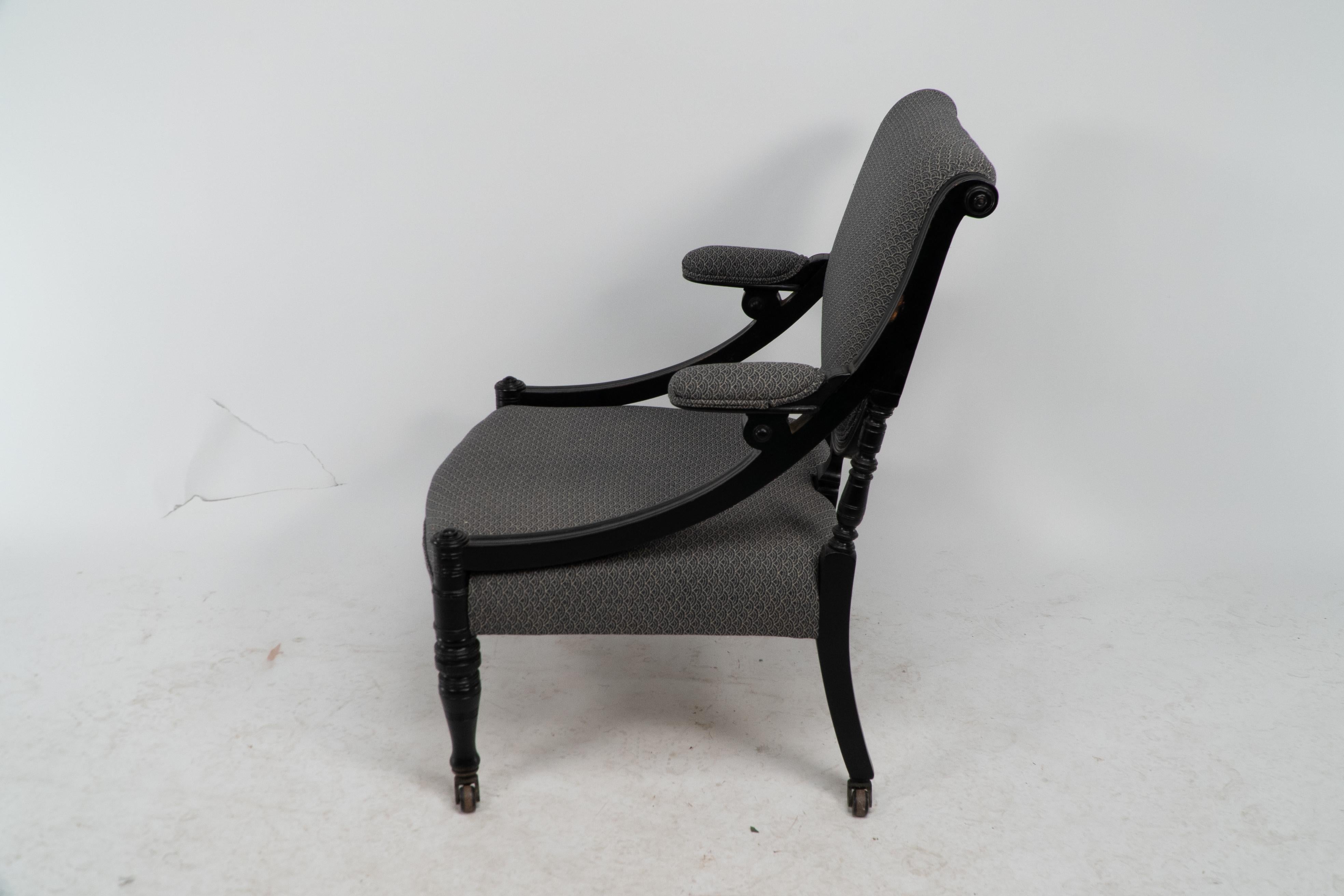 An Aesthetic Movement ebonized & upholstered armchair with sweeping side rails. In Good Condition For Sale In London, GB