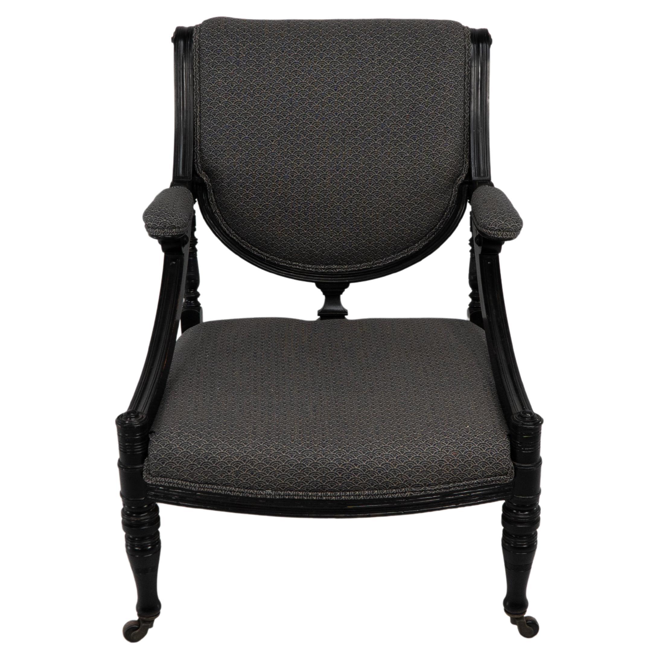 An Aesthetic Movement ebonized & upholstered armchair with sweeping side rails.