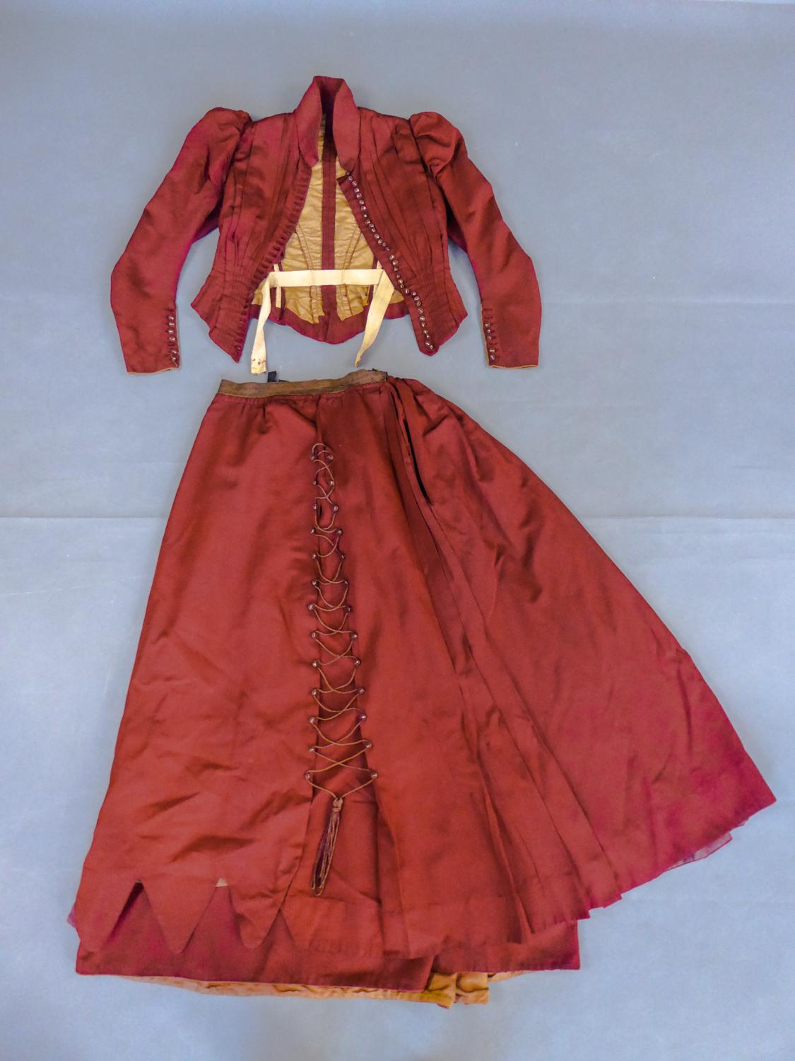 Circa 1895/1900
England
 
A deep red faille or ottoman silk set with bodice and skirt for riding during the Belle Epoque. Fitted boned bodice with small basques and long shaped sleeves with small gigot at the shoulders. Work of sewn pleats at the