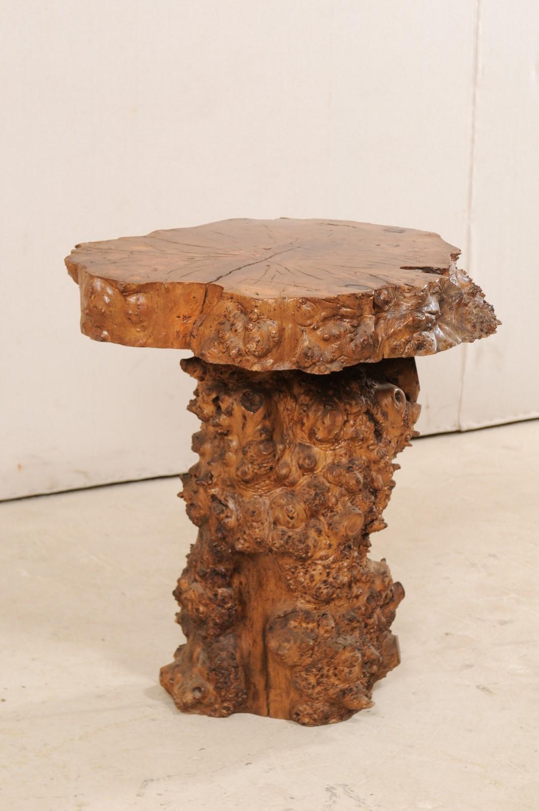A European burl slab top side table from the early 20th century. This rustic little antique table is comprised of a thick slab top of live-edge burl wood, displaying it's beautifully formed rings throughout the center, raised upon a column style