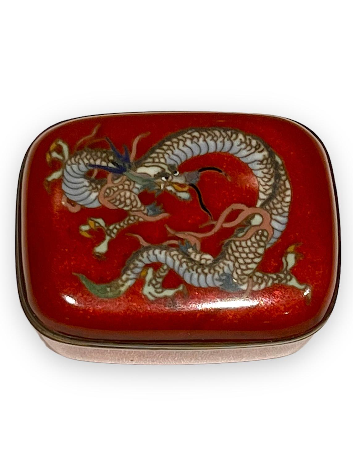 A Exquisite Japanese Cloisonne Enamel Box and Cover. 19th C
Meiji Period
Of rounded rectangular form, worked in silver wire with an intricate colorful dragon, reserved on a apple red metallic ground with silver rims and lined with silk