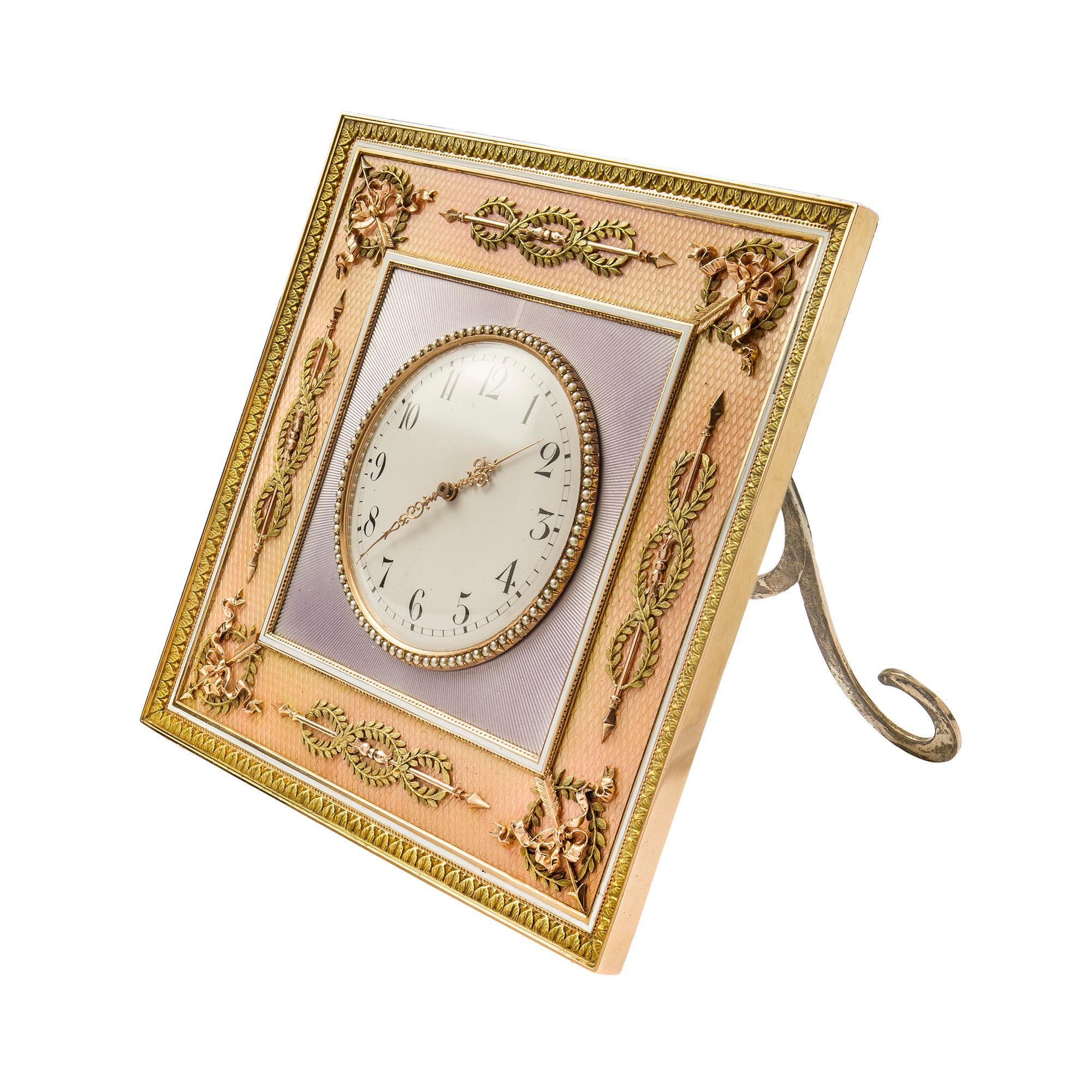 An Important Fabergé two-colour gold-mounted guilloche enamel desk clock, marked Fabergé, square, with circular seed-pearl bezel on lilac sunburst guilloché ground, the border enamelled in translucent salmon pink over a moiré guilloché ground, all