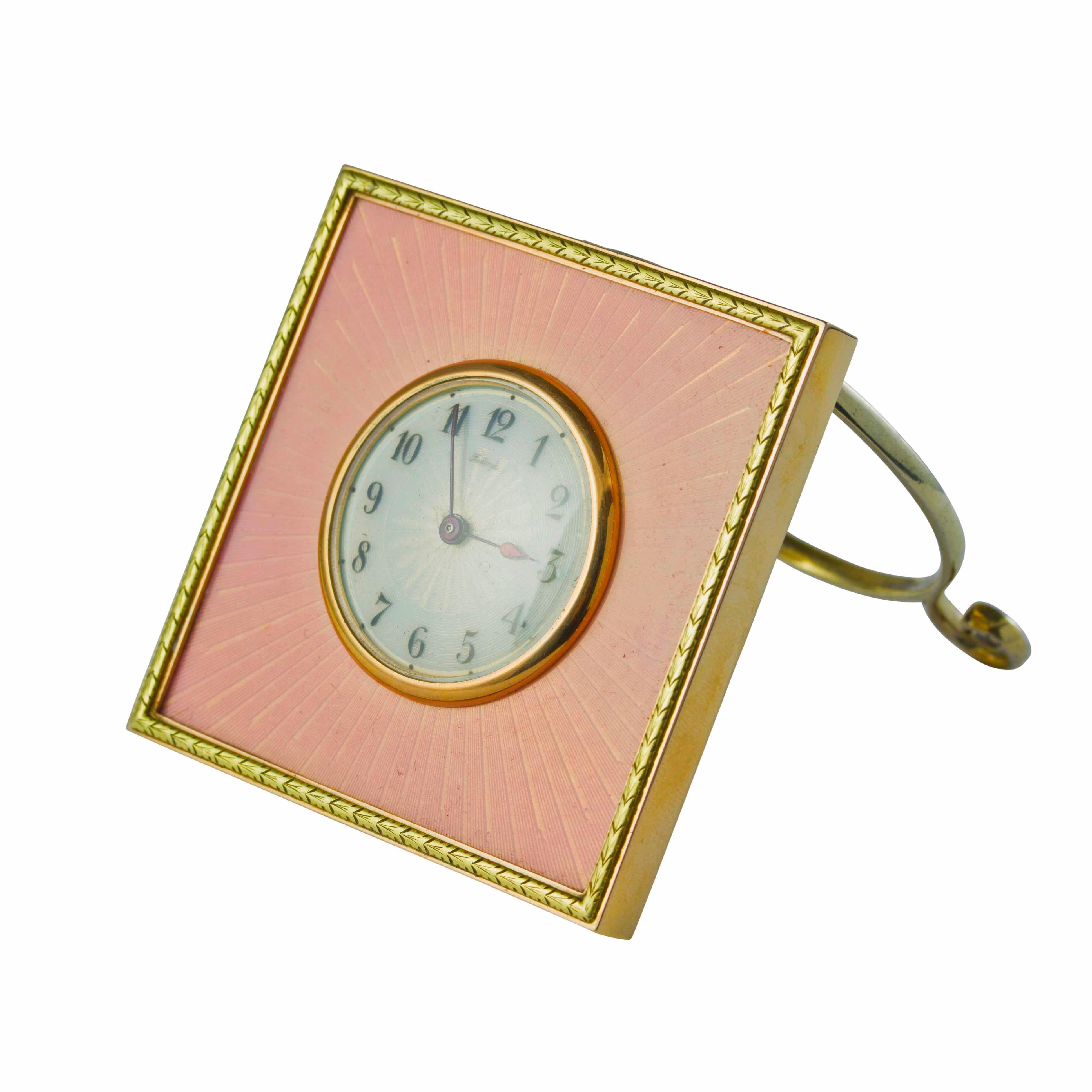 A Fabergé gold mounted silver-gilt and enamel desk clock, the square surface enamelled translucent pink over sunburst guilloche ground within laurel leaf border, centred with opalescent white enamel dial with black Arabic chapters signed Faberge