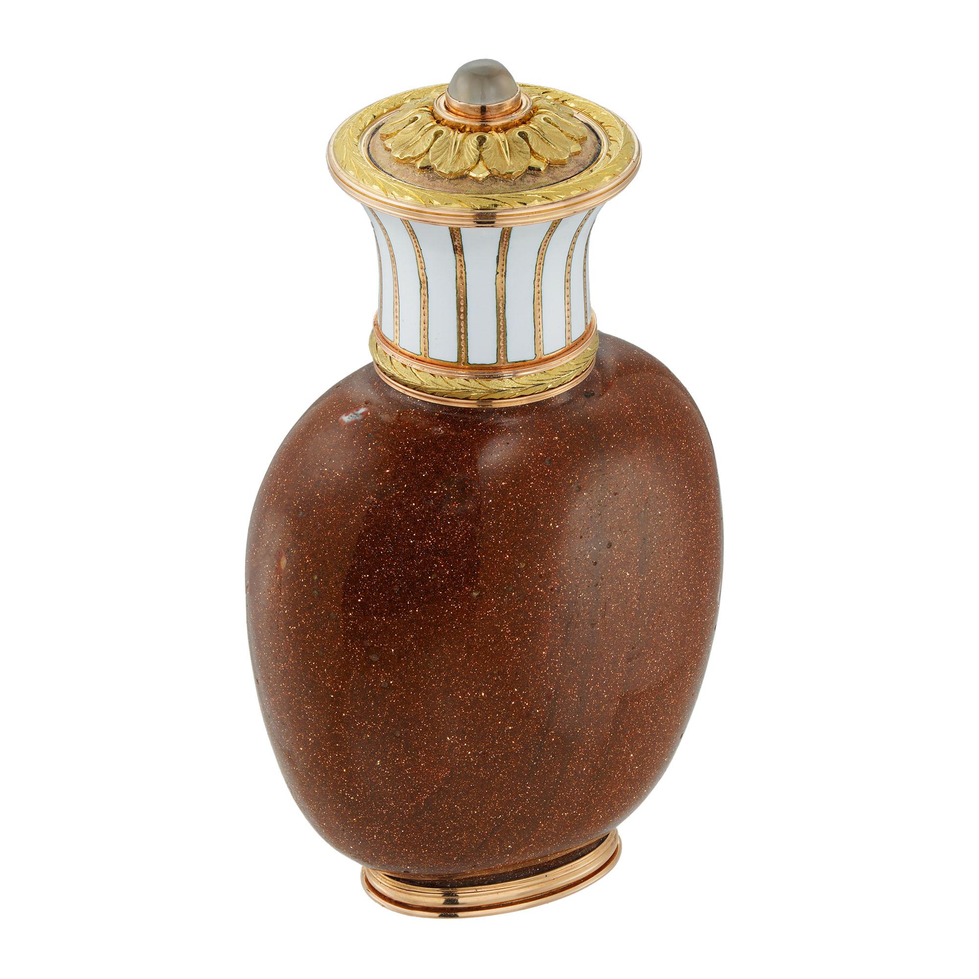 A Fabergé goldstone-glass, gold, and white enamel scent bottle, the vessel made of goldstone-like glass, with a slightly tapering rose-gold ridged base and rose gold hinged flared cap with a yellow gold laurel engraved band and opaque white enamel
