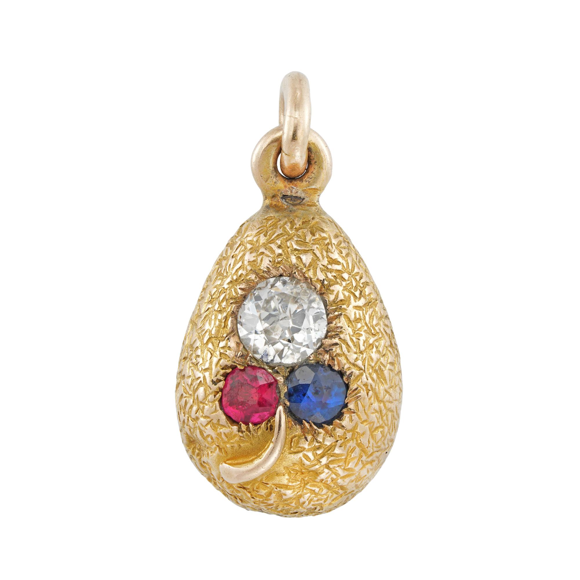A Fabergé jewelled egg pendant, the yellow gold chased body mounted with an old-cut diamond estimated to weigh 0.3 carats, a round faceted ruby and a round faceted sapphire forming the leaves of a pansy with gold stem, suspended by a gold pendant