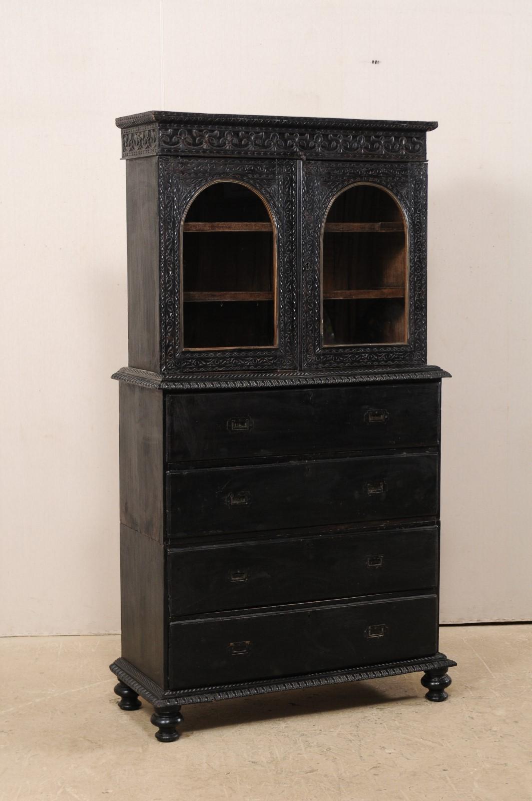 A tall British Colonial carved-wood secretary with display top from the turn of the 19th and 20th century. This fabulous antique piece from India is as beautiful as it is functional. The upper case is comprised of a pair of arched glass panel doors,