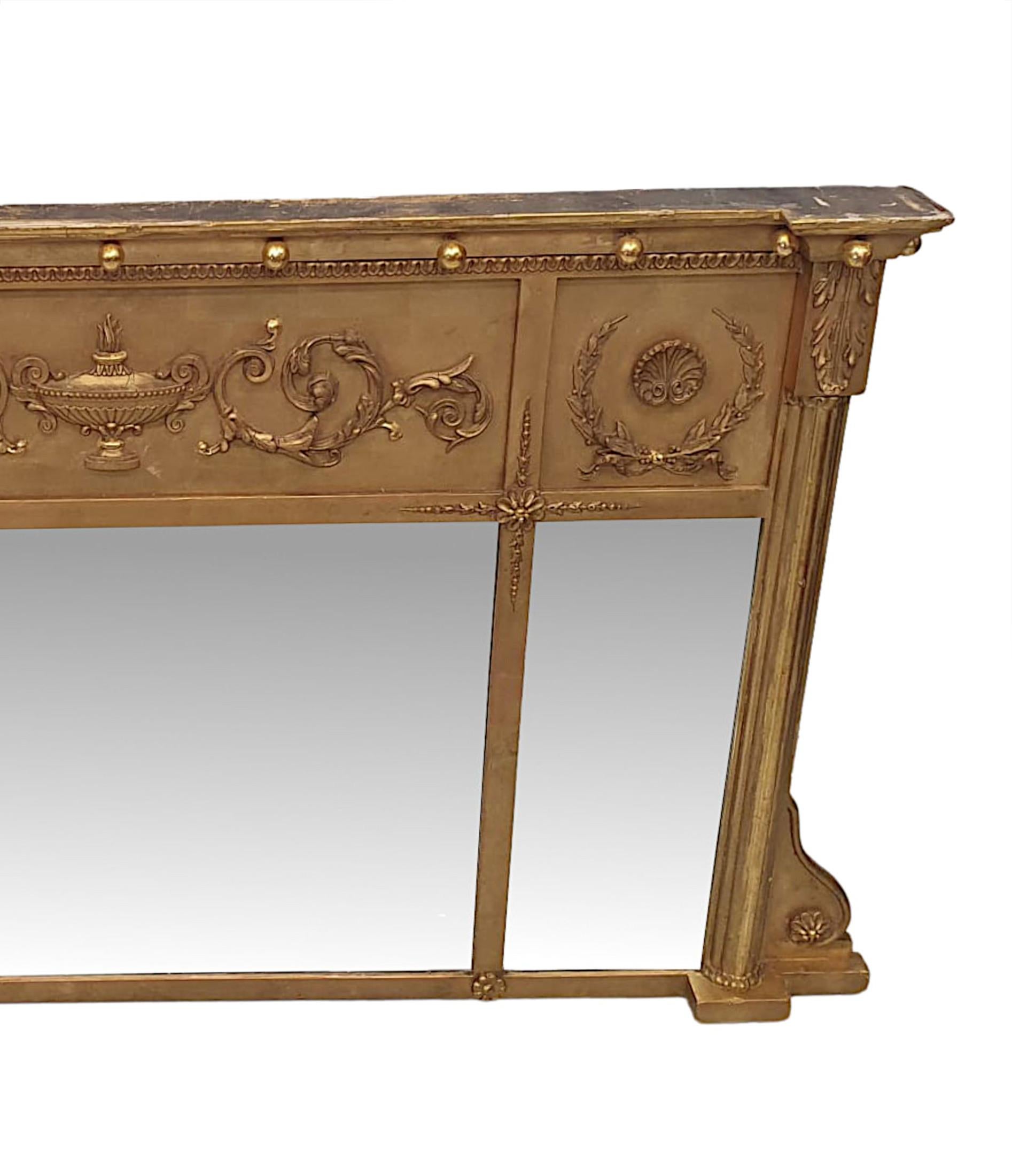 A fabulous Edwardian three compartmental giltwood overmantle mirror in the manner of Adams, of gorgeous quality and neat proportions. The central bevelled mirror glass plate of rectangular form flanked with two further glass plates, set within a