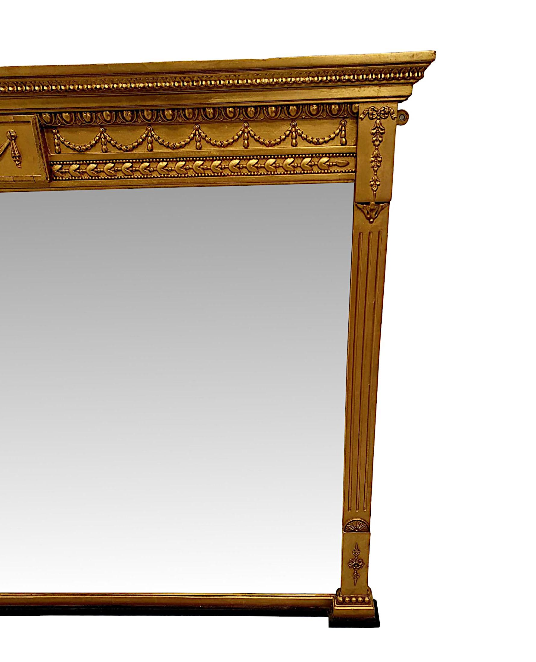 A fabulous Edwardian hall or overmantle mirror in the manner of Adams, of neat proportions and gorgeous quality.  The finely carved, fluted and moulded giltwood frame is surmounted with an overhanging stepped cornice above a panelled frieze with