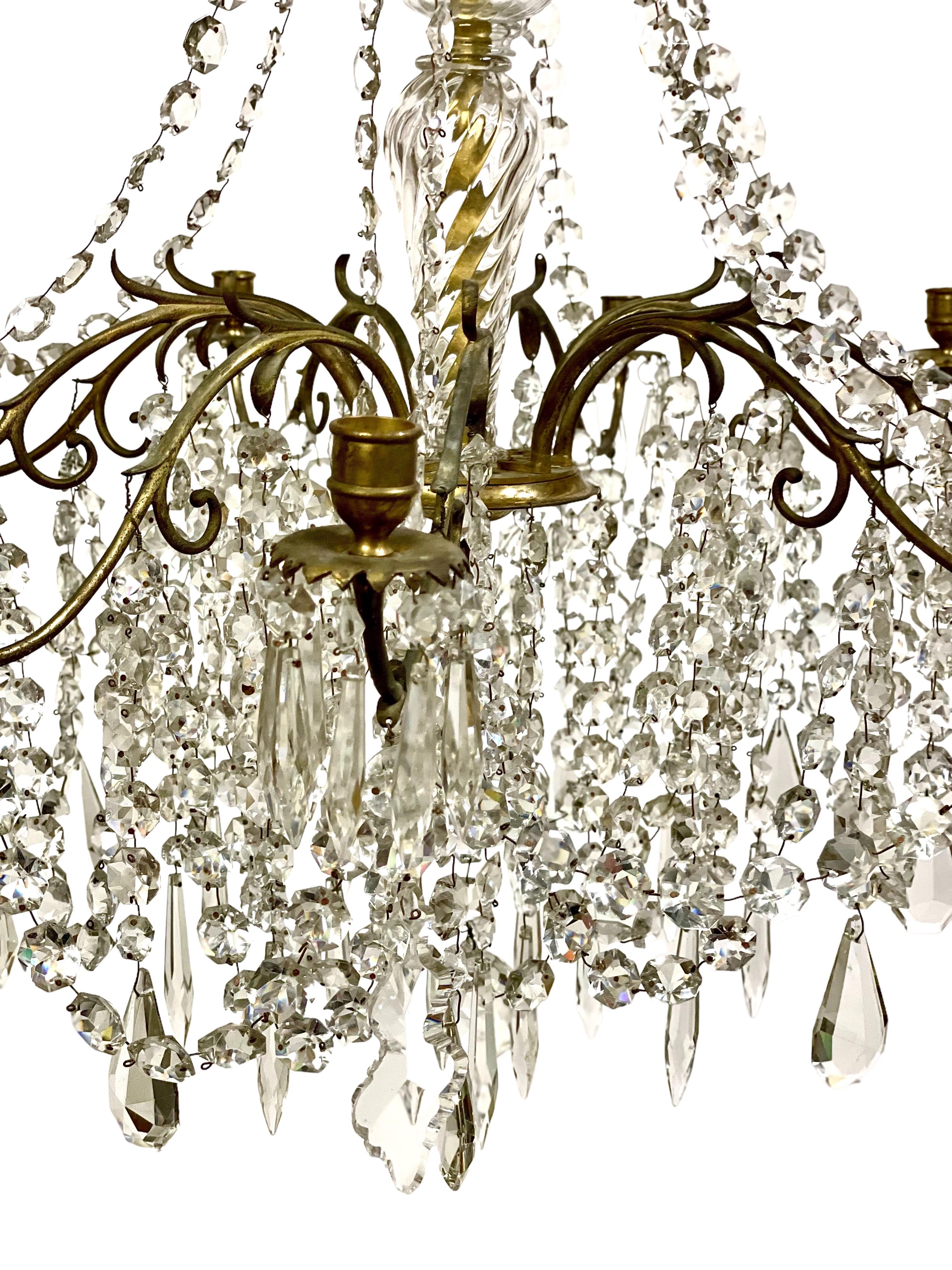 A fabulous, traditional gilt brass, bronze and cut crystal chandelier of nine lights, dating from the second half of the 19th century. This outstanding piece is richly decorated with sweeping crystal chains and glittering pendants encircling a