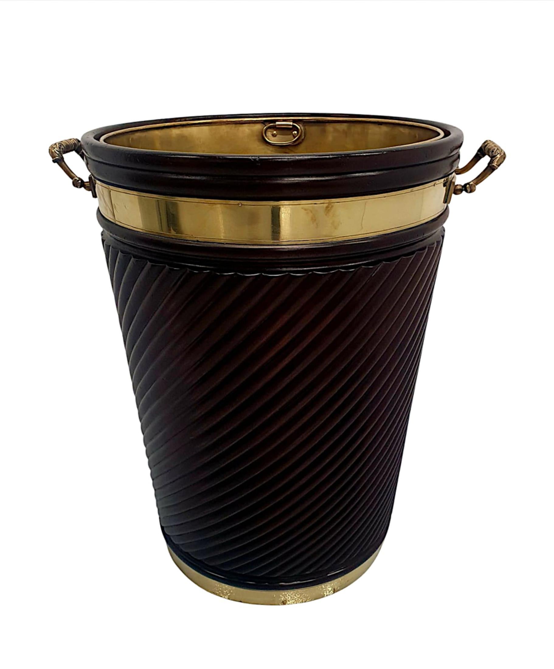 A fabulous Irish design mahogany brass bound peat bucket of exceptional quality, grand proportions and finely hand carved with rich patination and grain.  The moulded and reeded, brass bound body incorporates gorgeous spiral twist pattern detail and