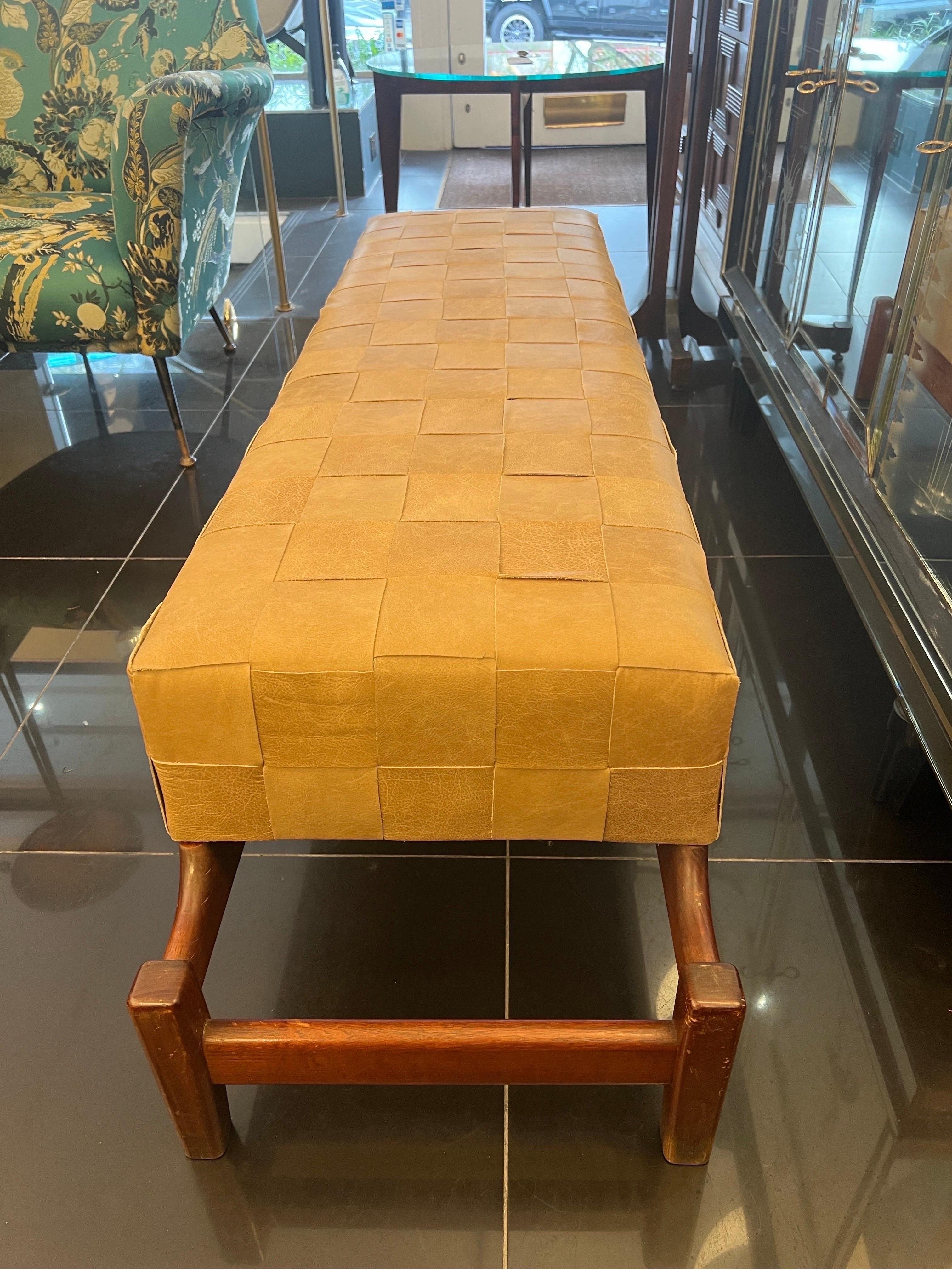 A large bench in sculptural form featuring an extended geometric design walnut frame standing on four legs with a built in rectangular cushion seat in sand colour woven leather.
C1960
Italy 