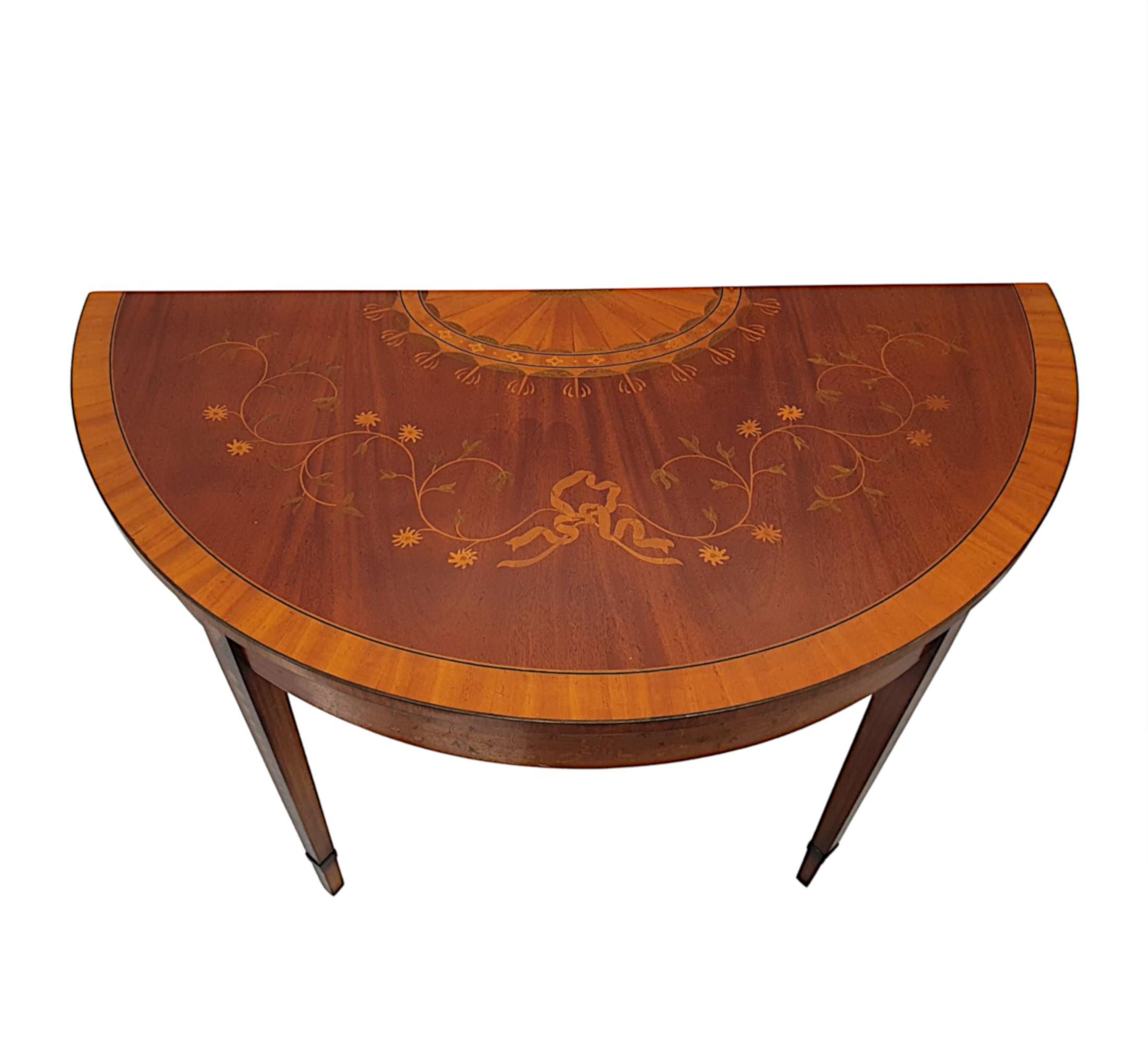 A fabulous quality mid-20th century hand-made mahogany demi-lune table. The cross banded and line inlaid moulded top with intricate marquetry inlay depicting an exquisite radiating fan accented with foliate motifs and a composition of centred ribbon