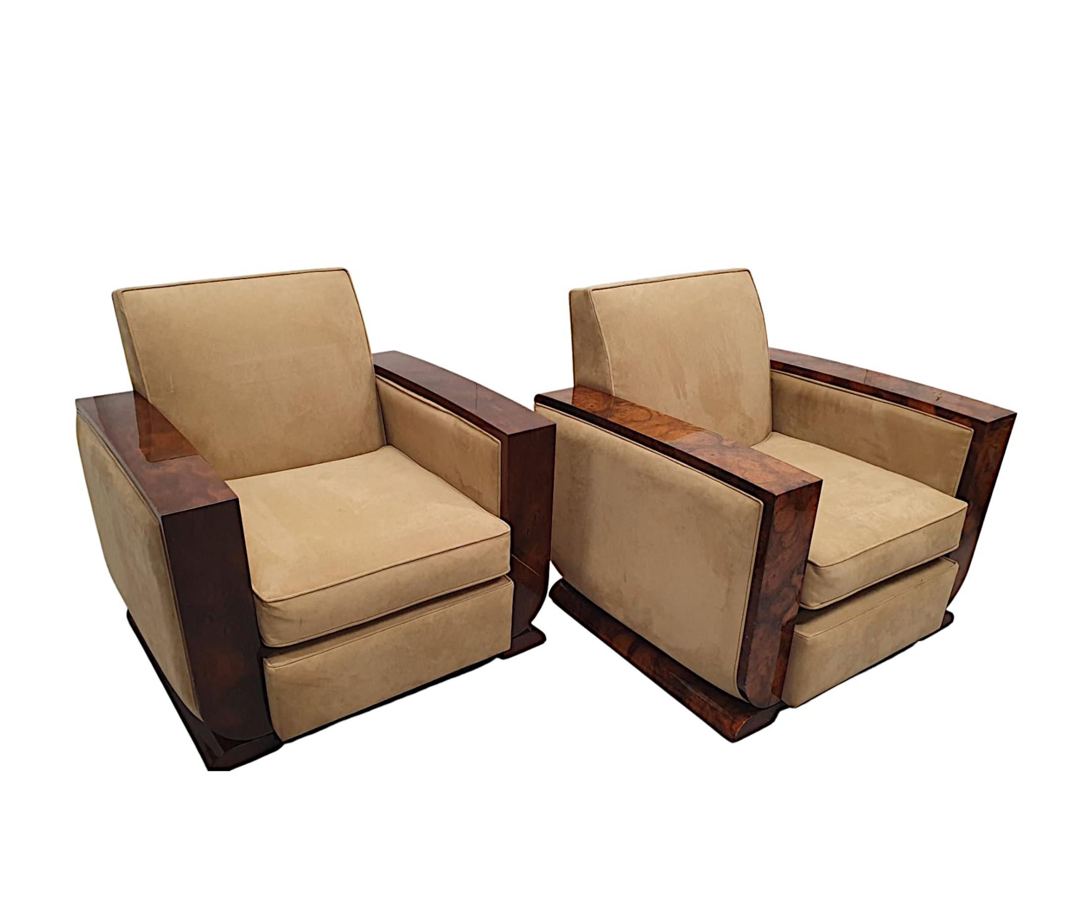 A fabulous pair of 20th Century armchairs in the Art Deco style. The cushioned back and seat beautifully upholstered in cream suede with piping detail, flanked by richly patinated burr walnut show timber detail to the arms.
