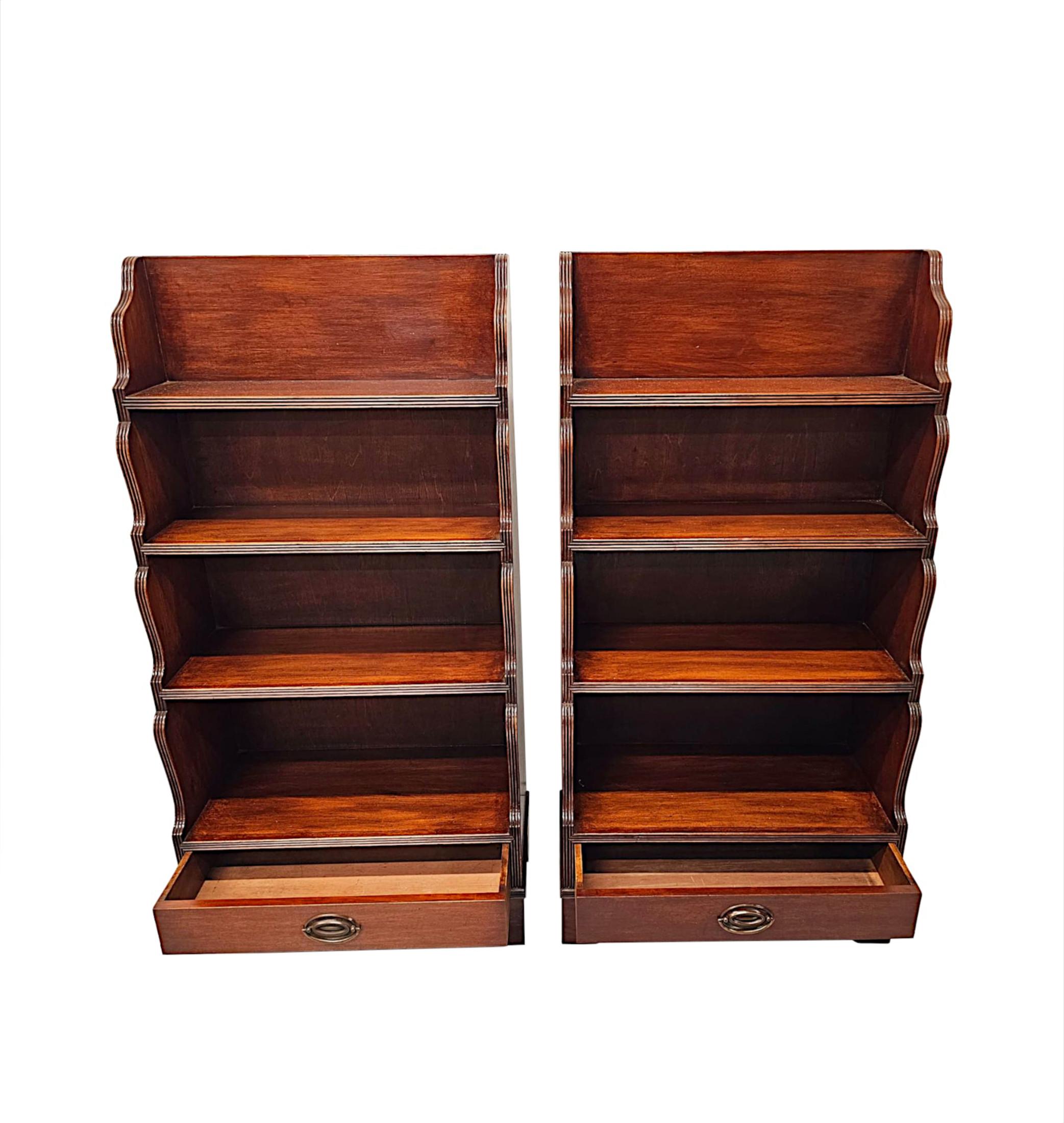 A fabulous pair of Edwardian mahogany open waterfall bookcases, finely carved, of neat proportions with deeply rich patination and grain.  The four moulded graduated shelves are set within gorgeous serpentine side supports, all with reeded border