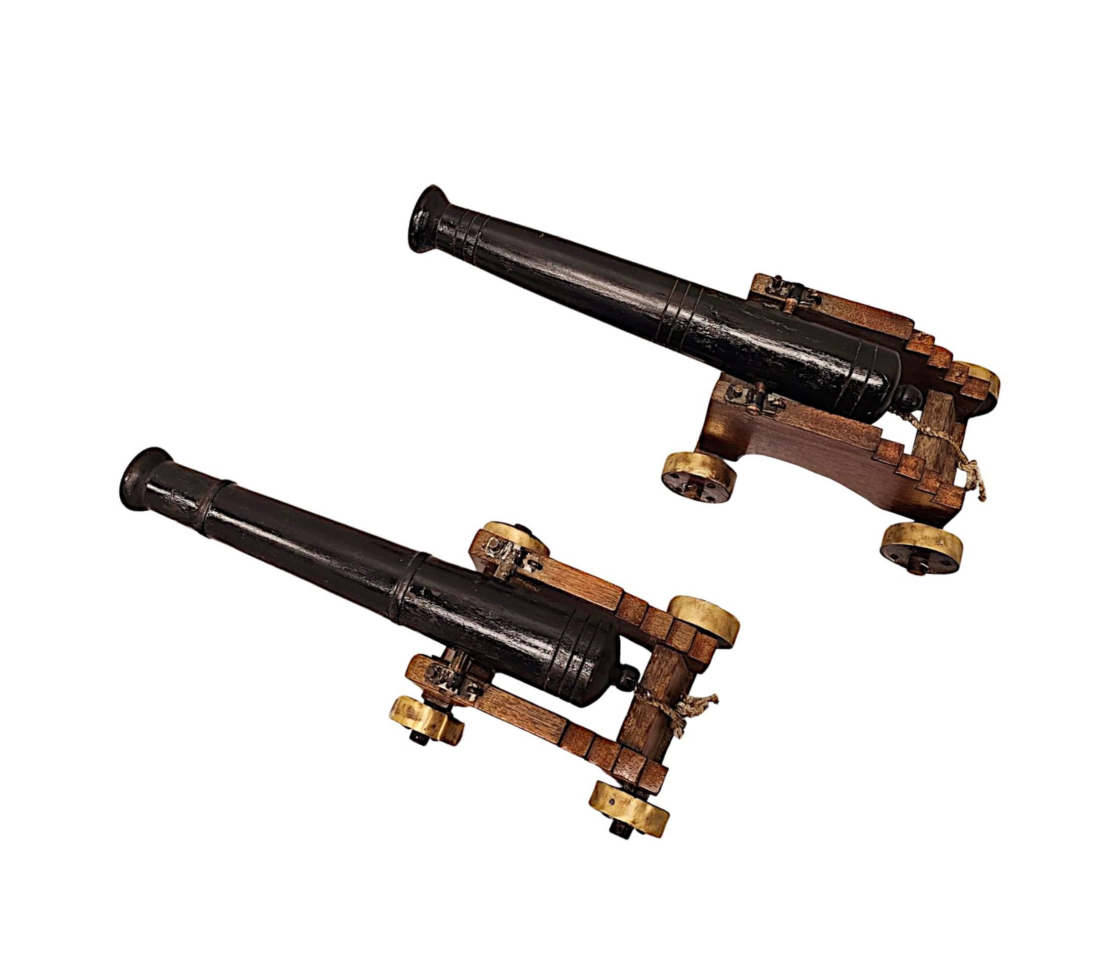 A fabulous and unusual pair of late 19th Century cast iron cannons of neat proportions with superb patination and colour, supported on a finely hand carved wooden base with brass wheels.  