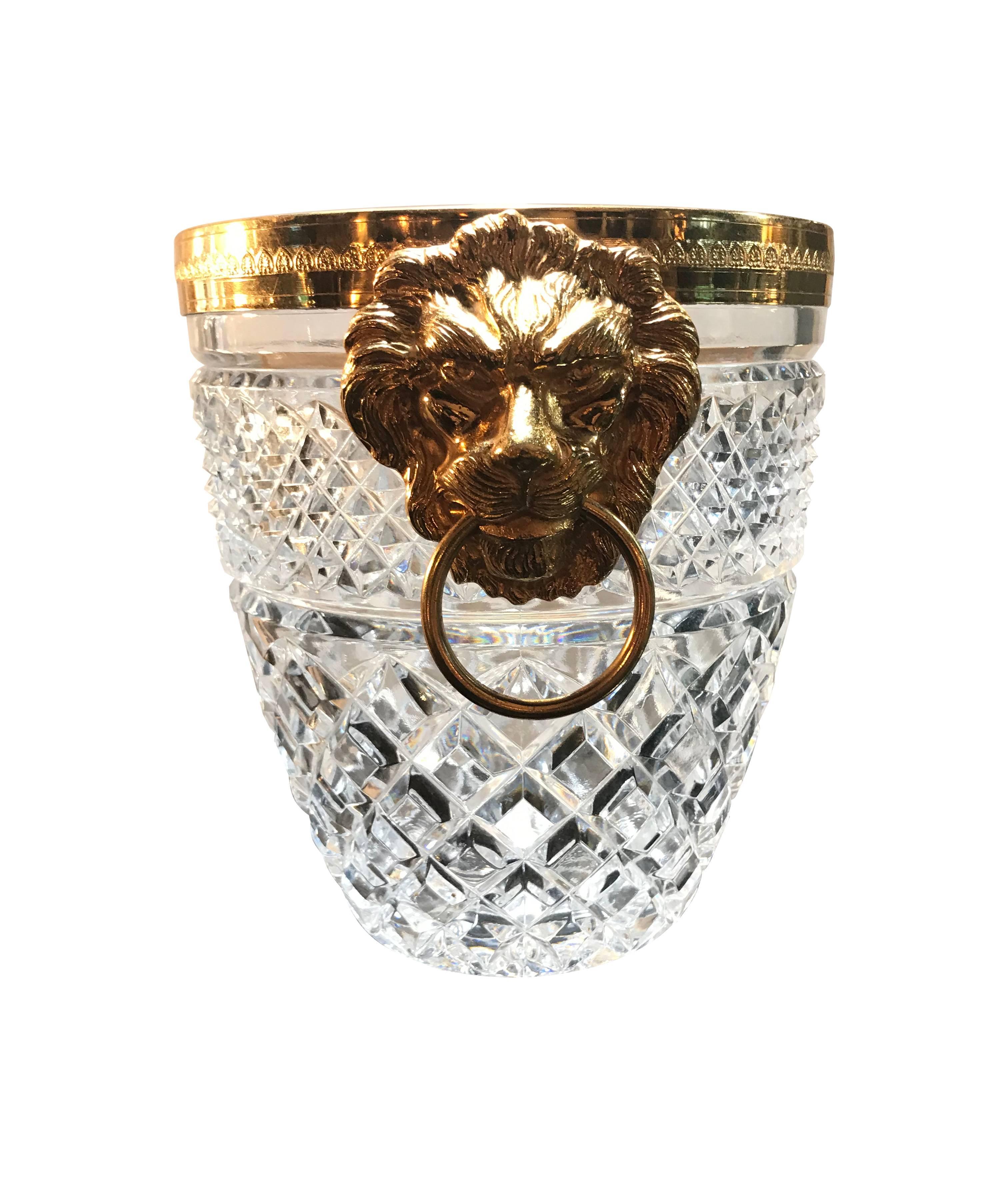 A faceted glass ice bucket with gilt metal rim and lion head handles on each side.