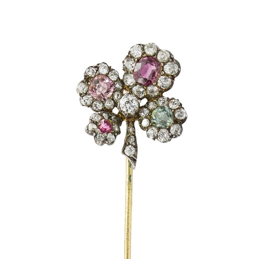 A late Victorian fancy coloured sapphires and diamond four-leaf clover pin, the brooch set with petals of fancy coloured sapphires, estimated to weigh a total of 0.60 carats, each set to the centre of an old-cut diamond cluster surround, with