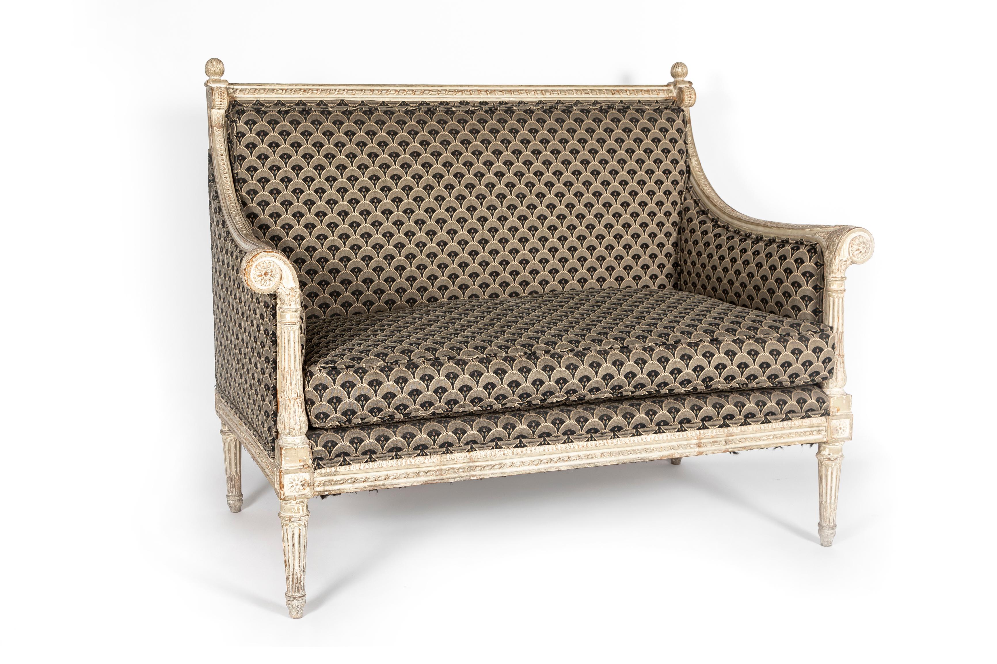 A Fantastic and Rare Pair of 18th Century Louis XVI Period French Marquises.  Each with a straight ribbon-wrapped reed crestrail with circular foliate-decorated finial to each corner, with guilloche-carved arms and scrolled arm supports, centered by