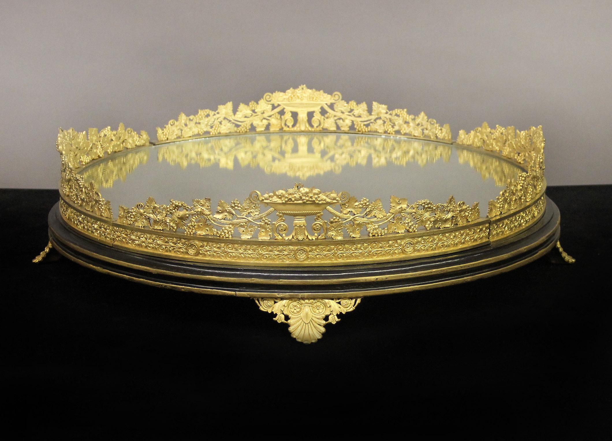 A Fantastic Late 19th Century Gilt Bronze and Mirror Surtout De Table

Circular form, cast with a grapevine bronze gallery and fruit filled centerpieces, a fitted mirror base and sitting on four shaped feet.

Surtouts de table began to appear