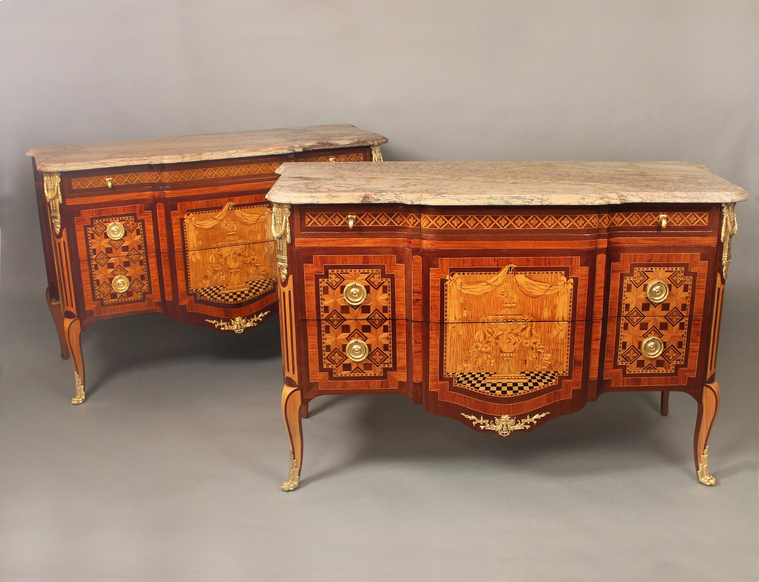 A fantastic pair of early 20th century gilt bronze mounted Louis XV style inlaid marquetry and parquetry commodes.

Each finely made commode with a shaped marble top over three short and two long dresser drawers, the long drawers centered by a