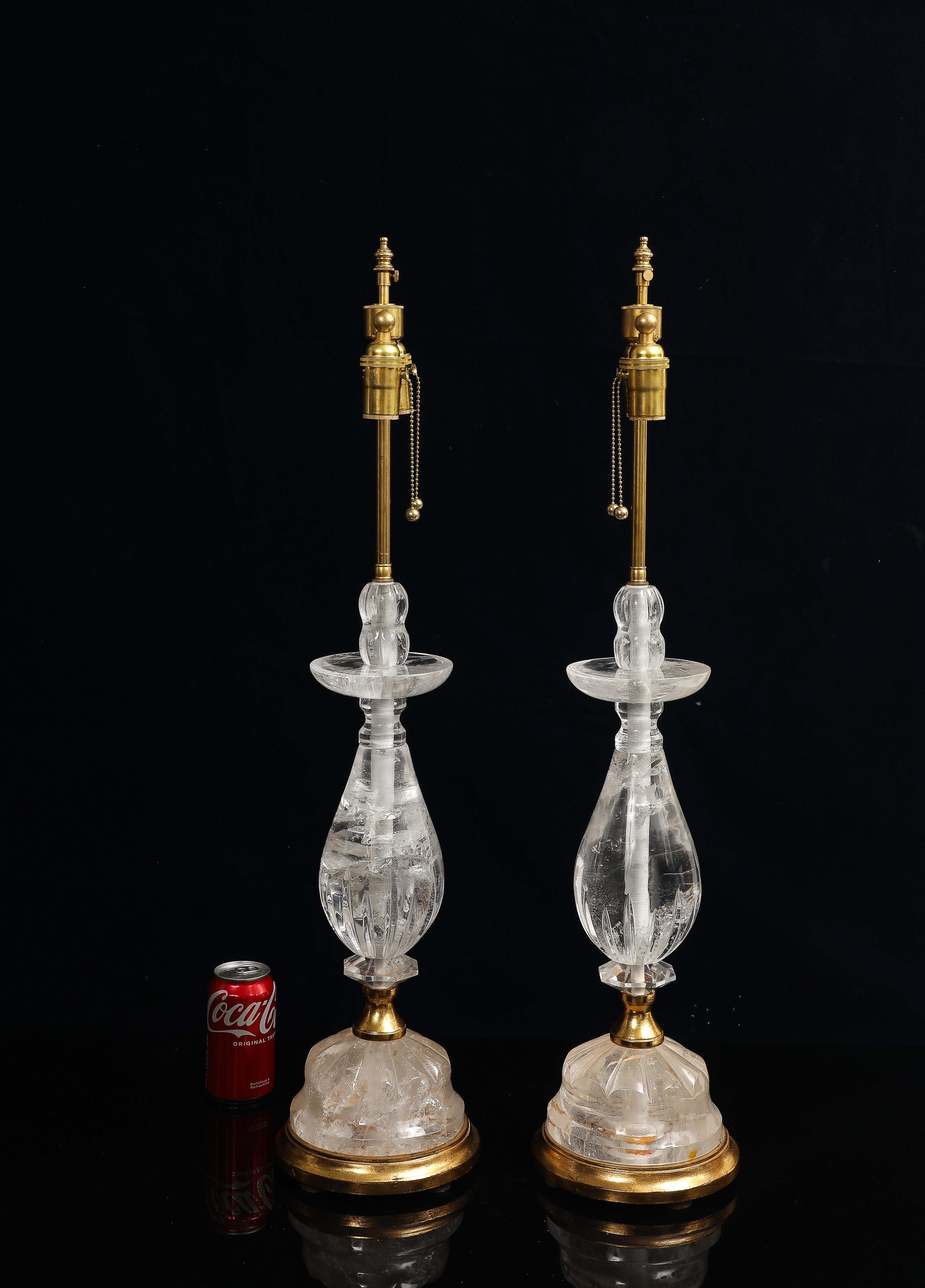 Fantastique paire de lampes de table Bagues en cristal de roche et bois doré du milieu du siècle. Chaque lampe présente un corps en cristal de roche clair, composé de multiples sections sculptées aux profils géométriques et arrondis variés. La