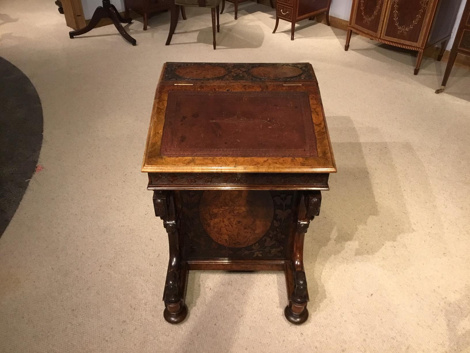 A fantastic quality burr walnut Victorian Period carved antique davenport. Having a sloping top retaining the original Moroccan leather tooled writing surface and a 