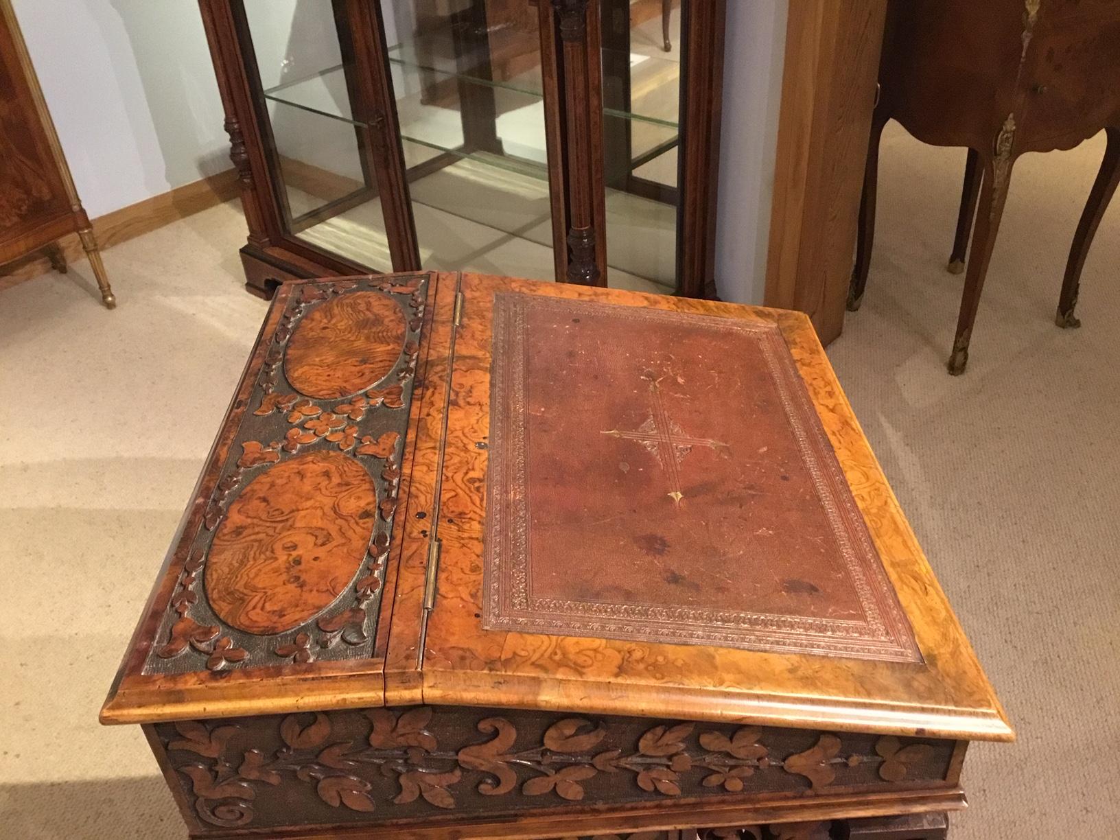 A fantastic quality burr walnut Victorian Period carved antique davenport. Having a sloping top retaining the original Moroccan leather tooled writing surface and a 