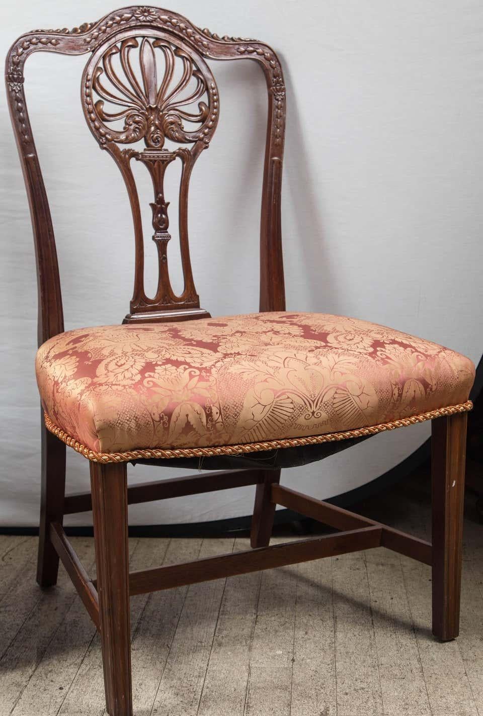 A fine set of 16 hand carved Hepplewhite dining chairs. 2 arms and 14 sides. Wood dowels and covered in a mauve silk.