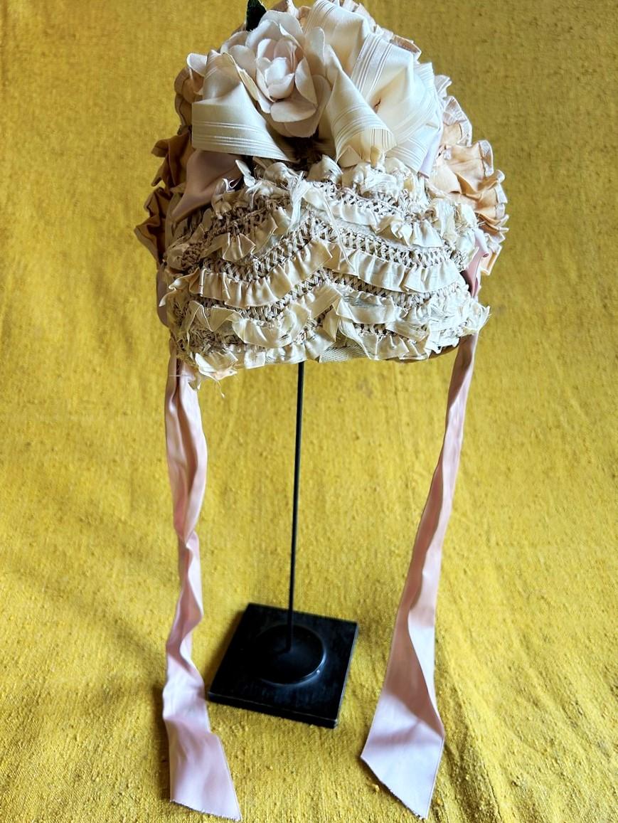 Circa 1860
France

Small straw hooded fashion bibi covered with a ruché of ribbons and falbalas dating from the French Second Empire. The bottom is made of a lace of cords with cream pleated ribbons (some gaps in the ribbons). Large cream ribbon