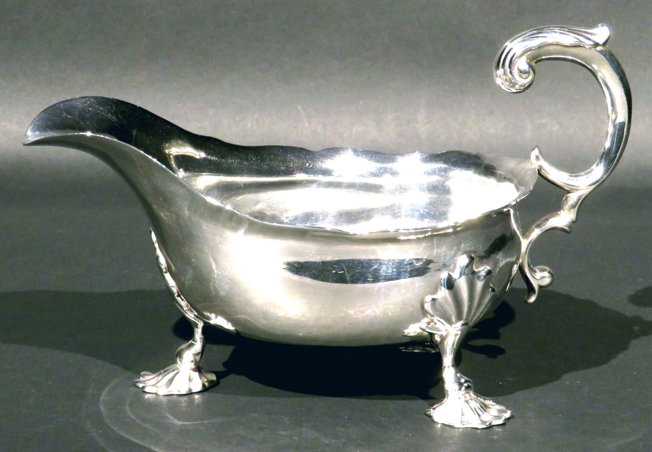 A very good & heavy 18th century Georgian sterling silver gravy boat, having a very ample bellied body engraved one one side with a heraldic crest, rising to a wavy rim with an applied foliate inspired scrolled handle. 
Raised overall on three