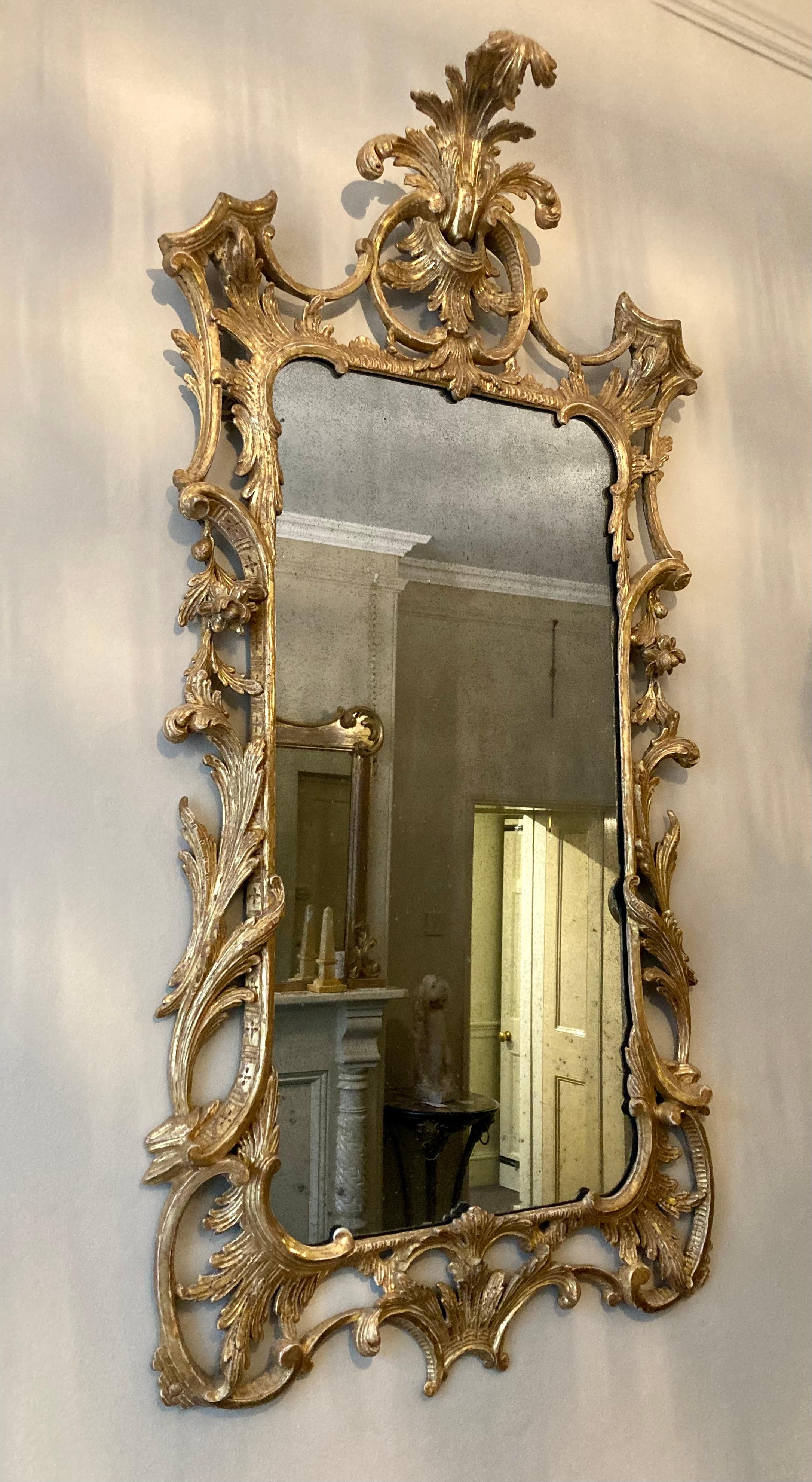 A beautifully proportioned carved  18th century period giltwood Chippendale wall mirror with acanthus leaf top, supported on 'C' shaped scrolls and trailing foliage surmounted on crisply carved leaf supports. The apron is decorated with 'C' scrolls