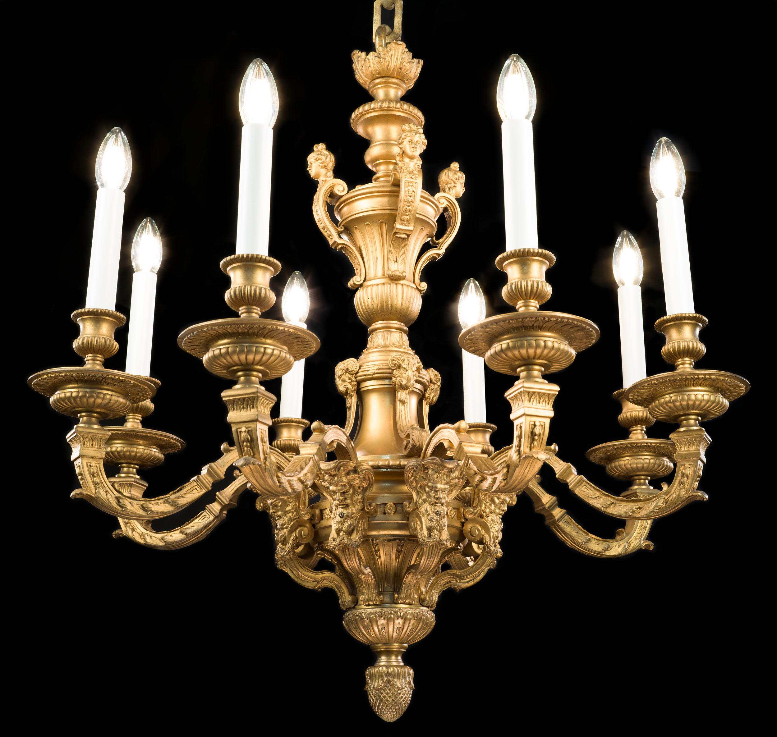 Un raffinato lampadario in bronzo dorato in stile Mazarin. L'ornato gambo centrale è decorato con volute e terminali, ariete e satiri, in stile barocco. Dal fusto centrale si dipartono otto rami, ciascuno con ornamenti foliati e gocciolatoi urnulari