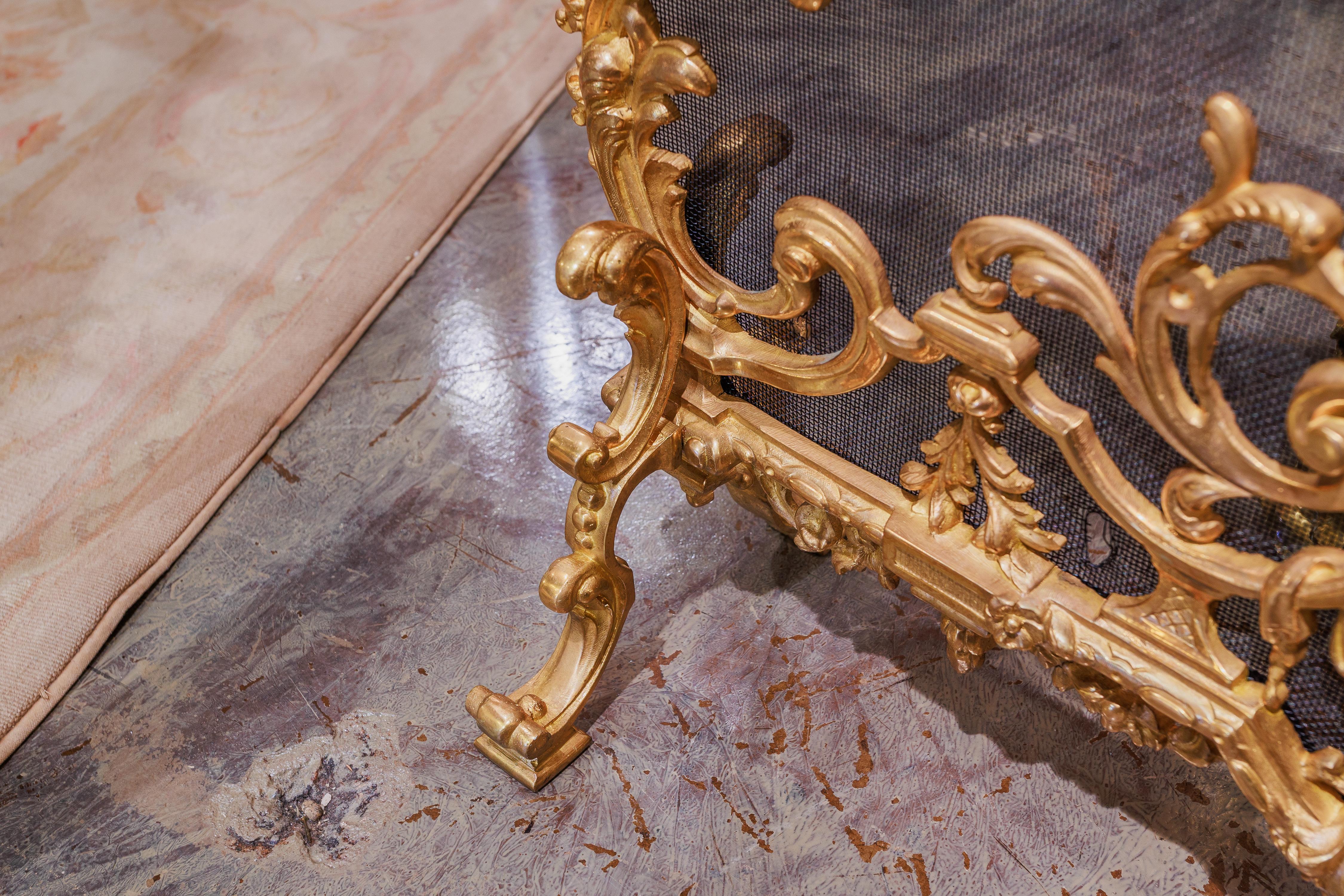 Un raffinato parafuoco francese Luigi XV in bronzo dorato del XIX secolo. Intricati dettagli in bronzo dorato con il Re Sole nel pannello centrale della maglia