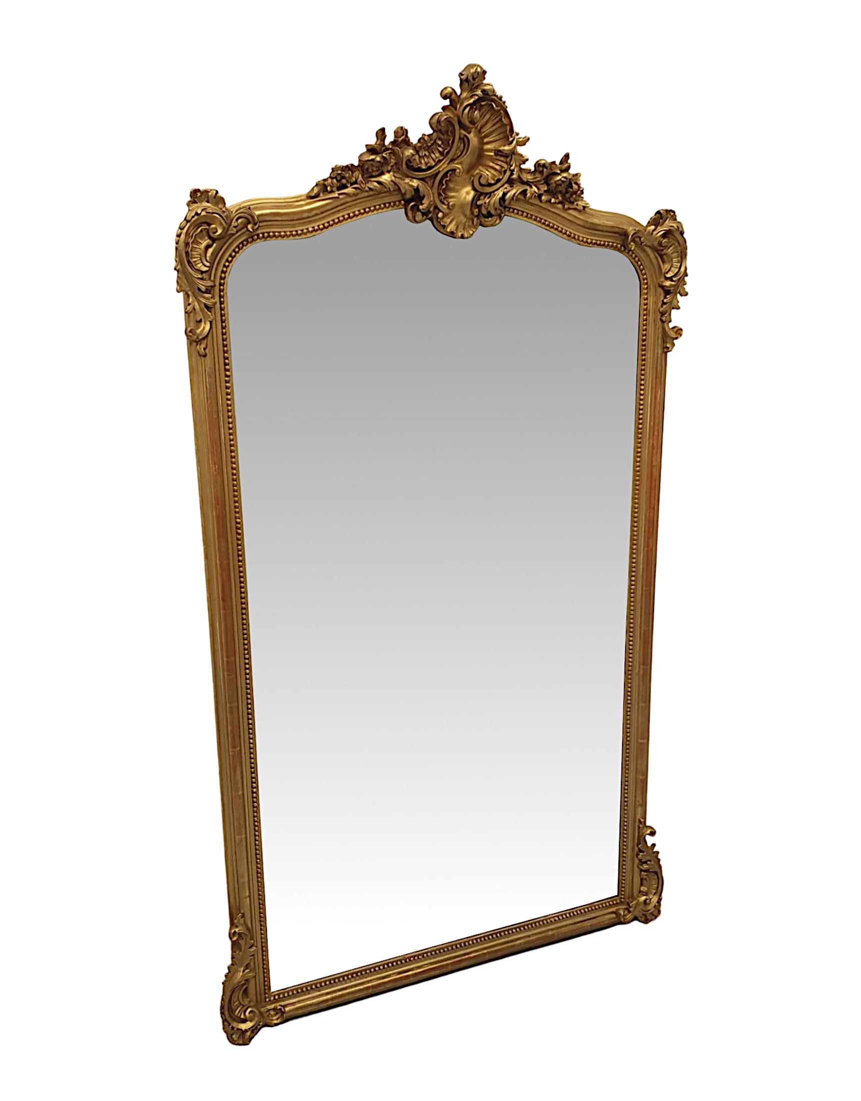 A fine 19th century giltwood overmantle or hall mirror. The original bevelled mirror glass plate of shaped rectangular form is set within a stunningly hand carved and moulded giltwood frame with beaded border. Surmounted with an elegantly ornate,